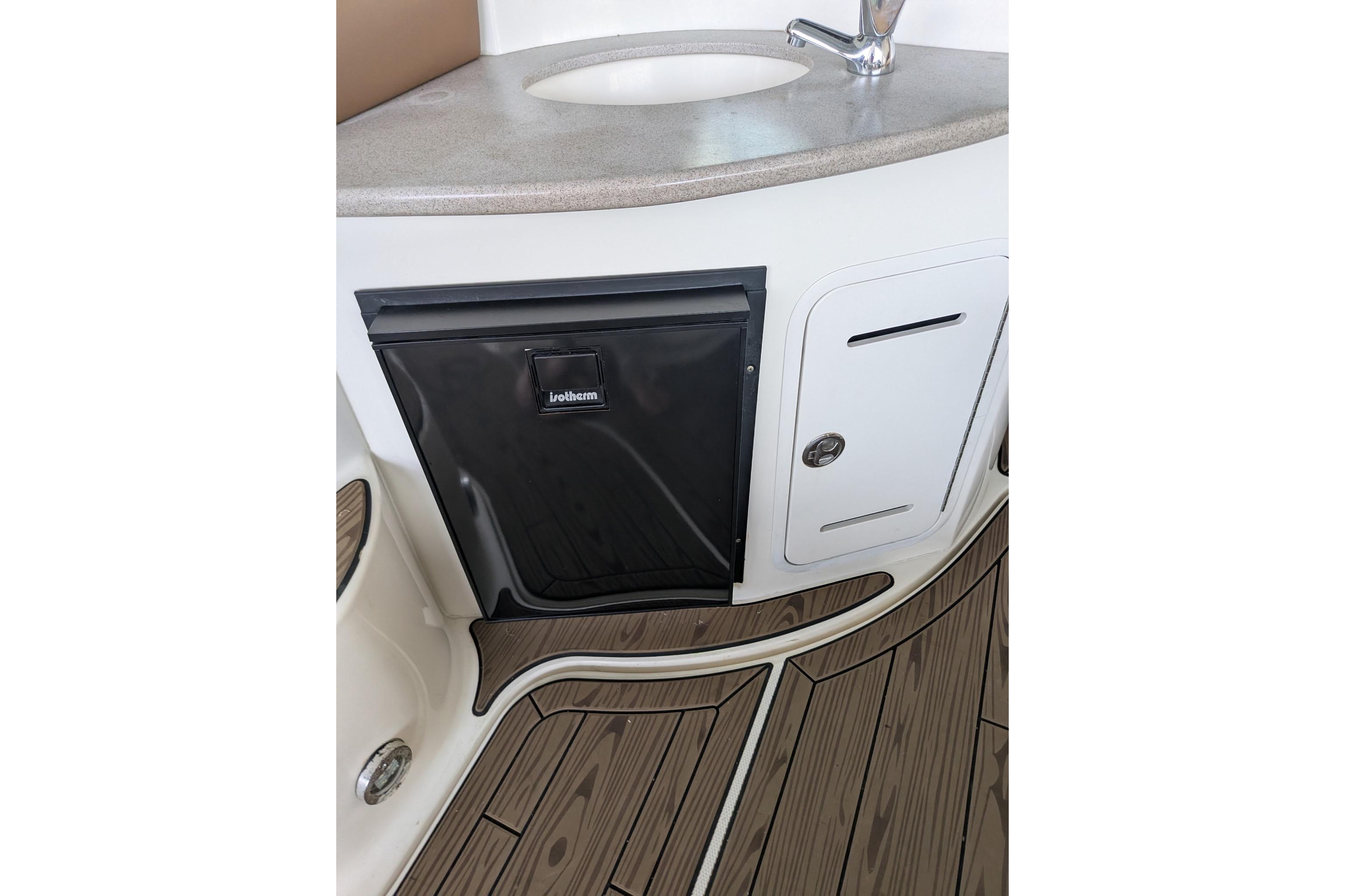 2002 Sea Ray Sundancer 320 interior with sink, fridge, and wood flooring.
