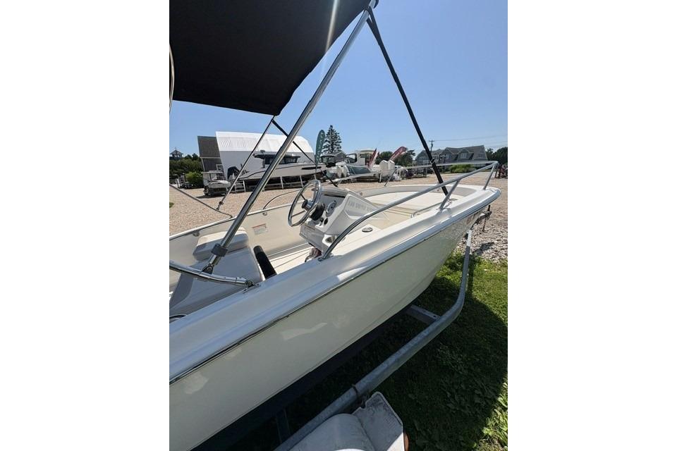 2024 Boston Whaler 130 Super Sport boat with canopy, parked on a trailer.