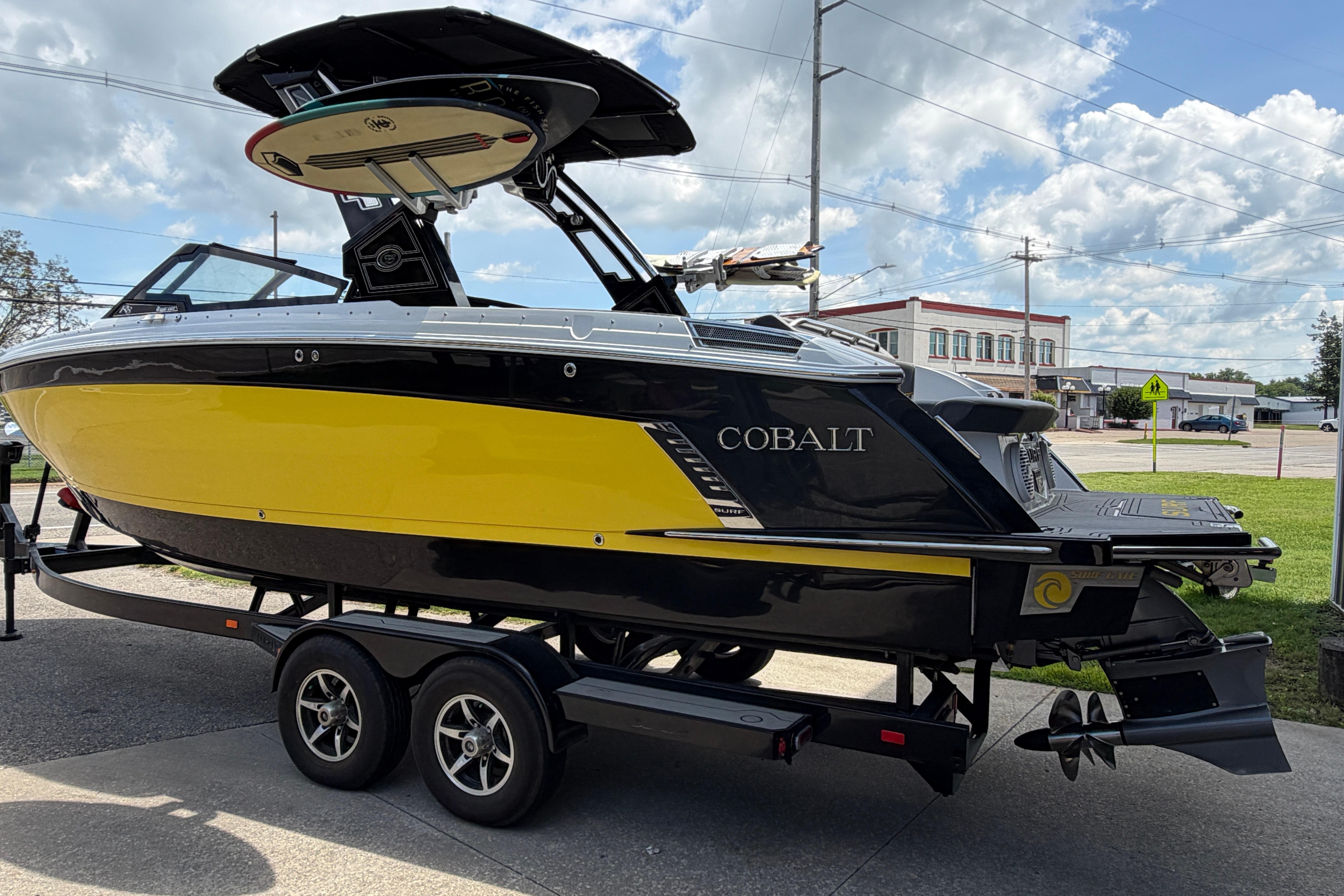 2021 Cobalt R8 Surf boat in yellow and black on a trailer, parked outdoors.