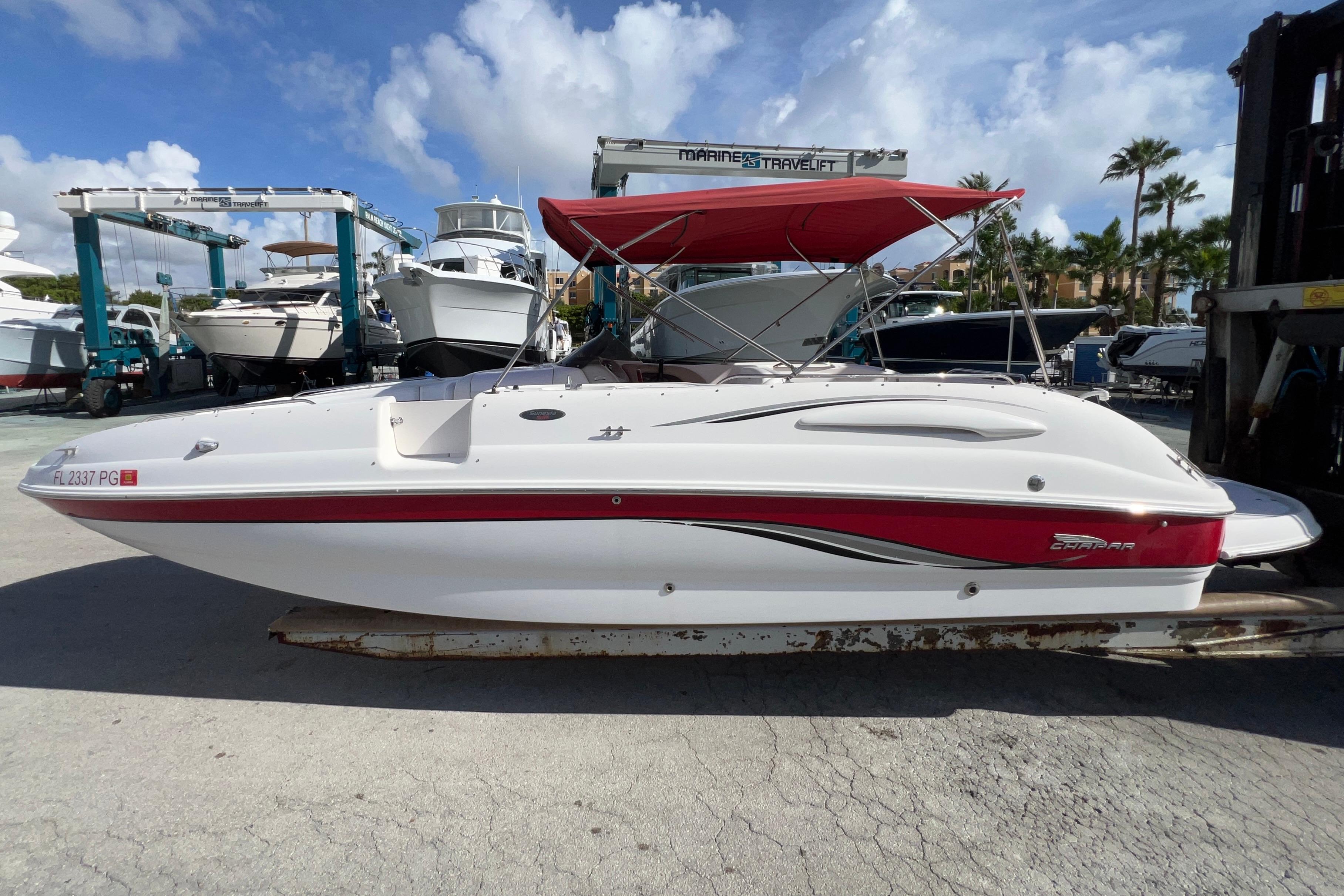 2002 Chaparral 232 Sunesta boat with red accents and canopy, docked under blue sky.