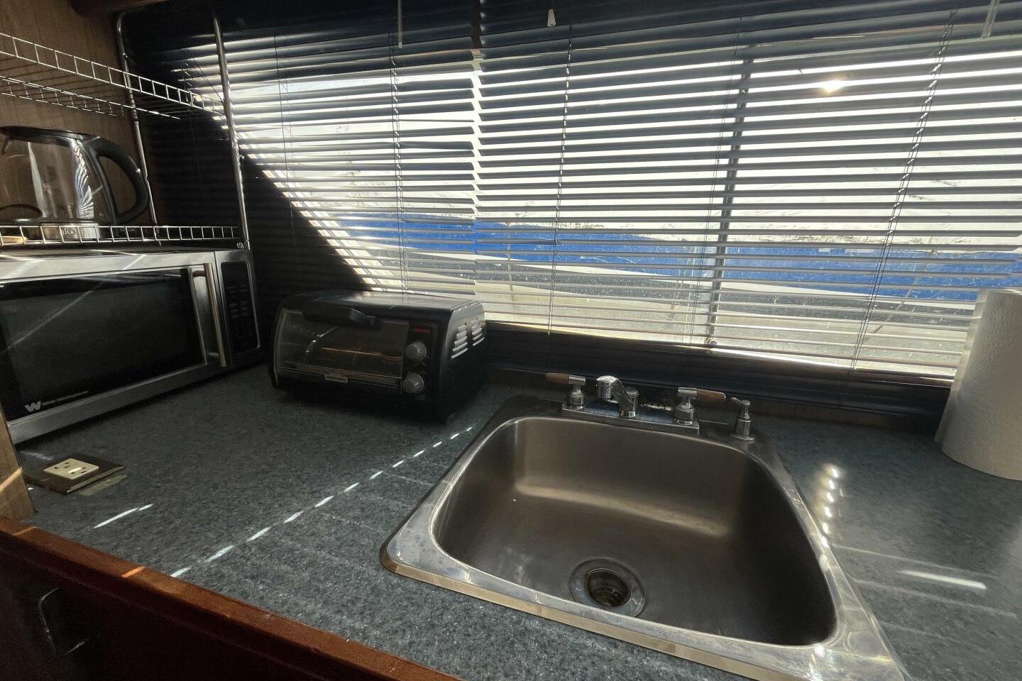 Compact kitchen area in a 1976 Richardson 52 Thorfinn boat with sink, microwave, and toaster.