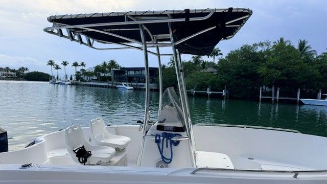 2004 Wellcraft 180 Fisherman with T-top, on calm water, surrounded by palm trees.