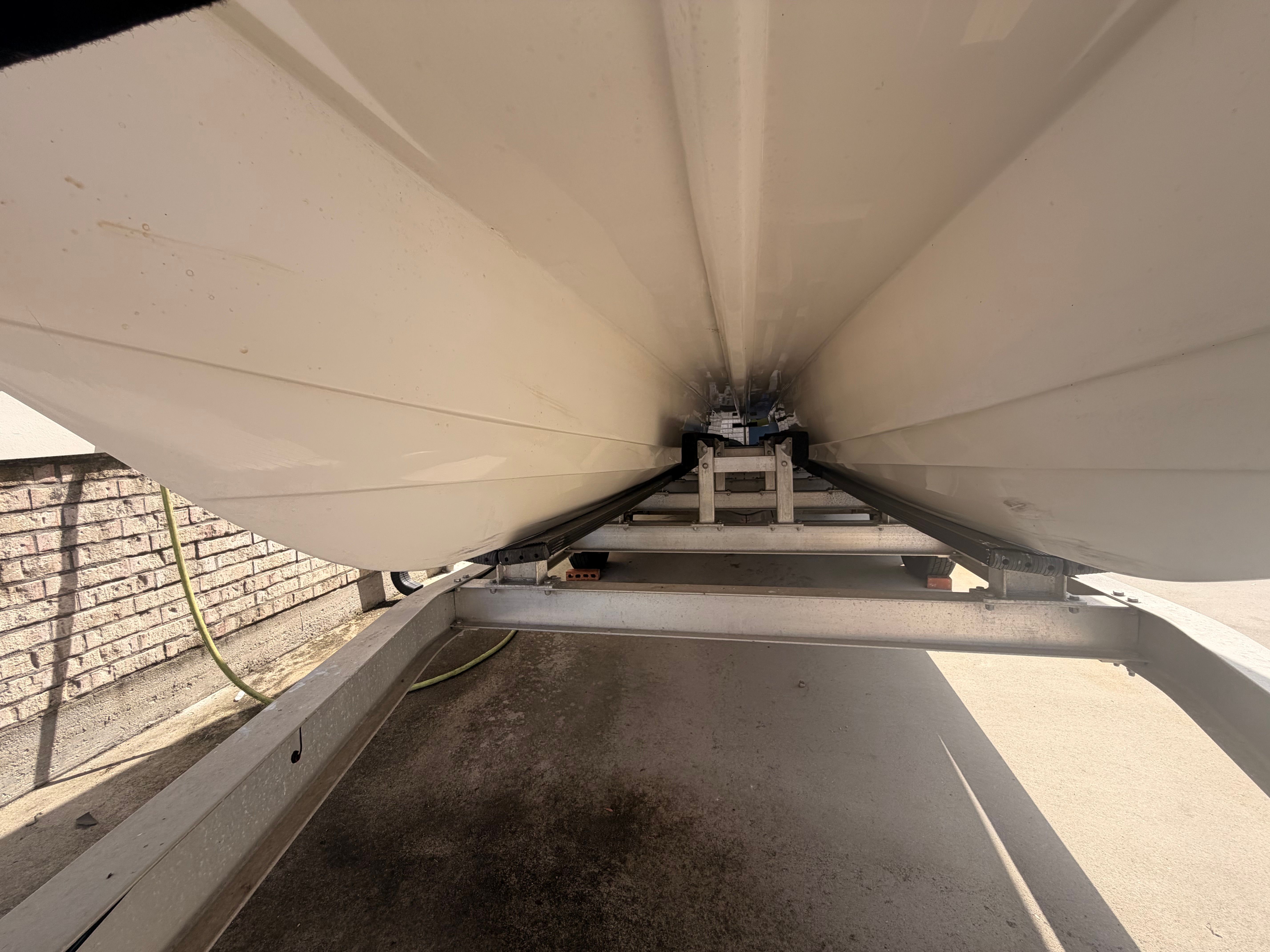 Underside of a catamaran boat on a trailer, ready for transport.