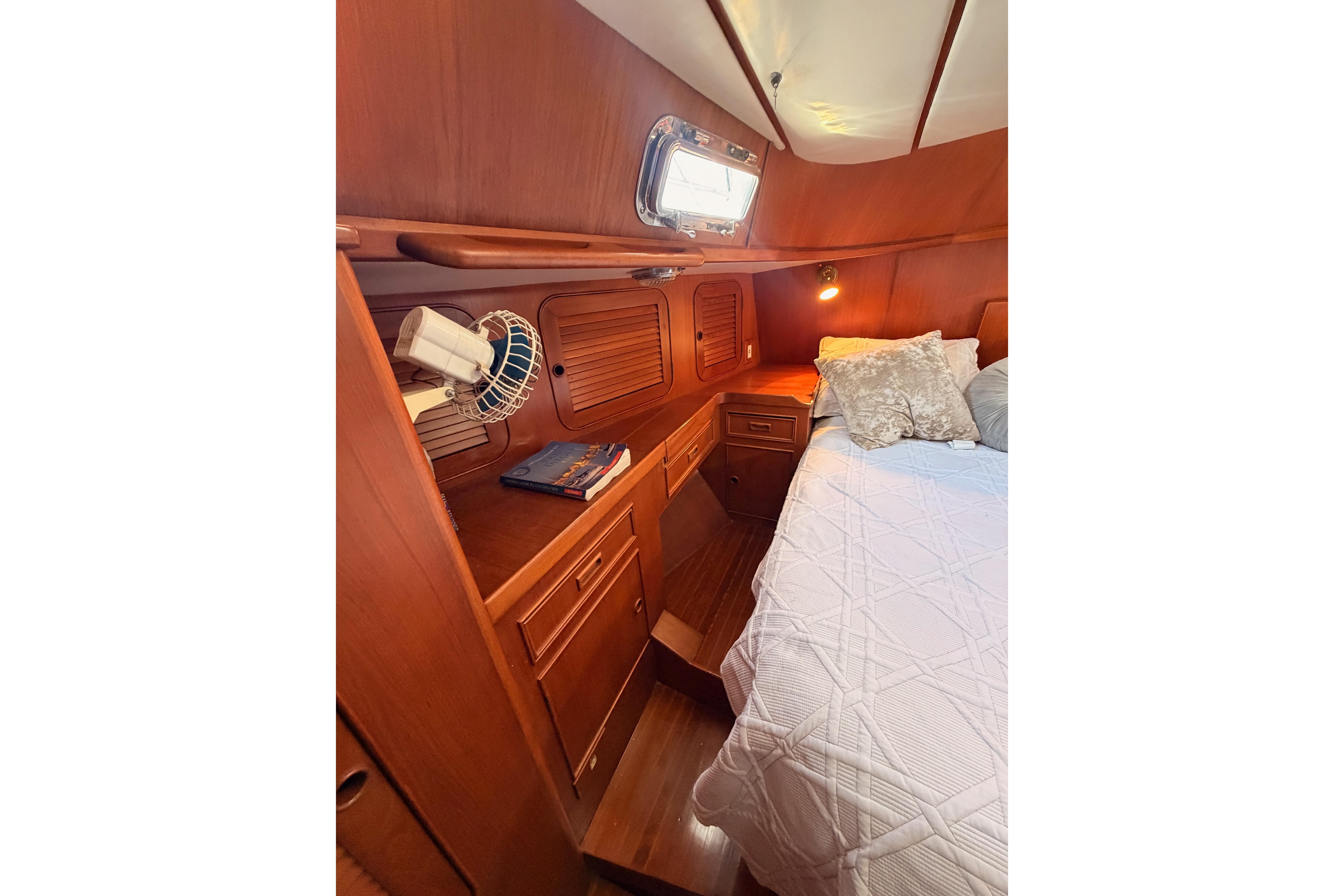 Cozy cabin interior of 1991 Hylas 51 yacht with wooden furnishings and bed.