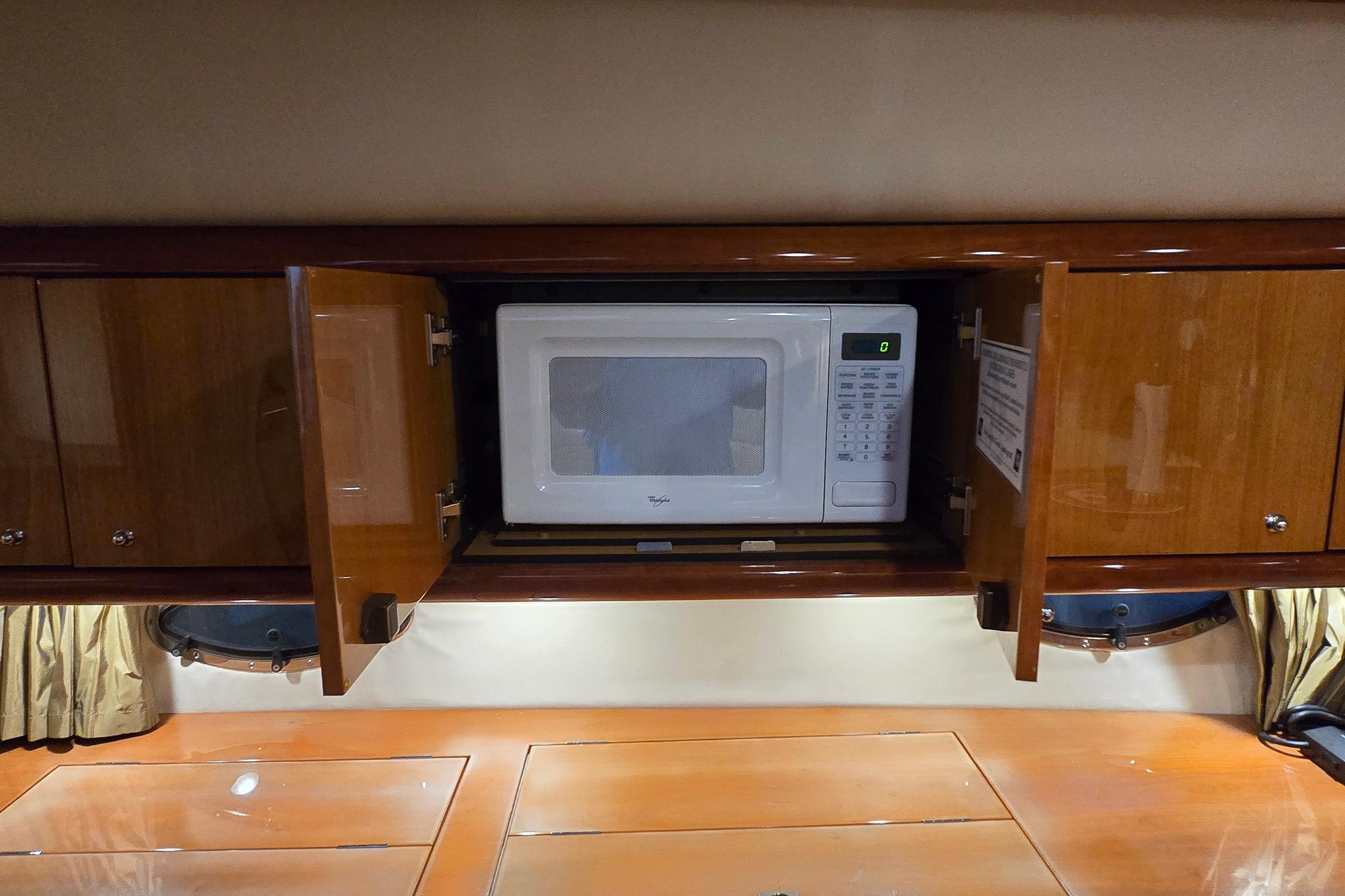 Microwave in wooden cabinet aboard 2004 Sunseeker Camargue 50 yacht kitchen.