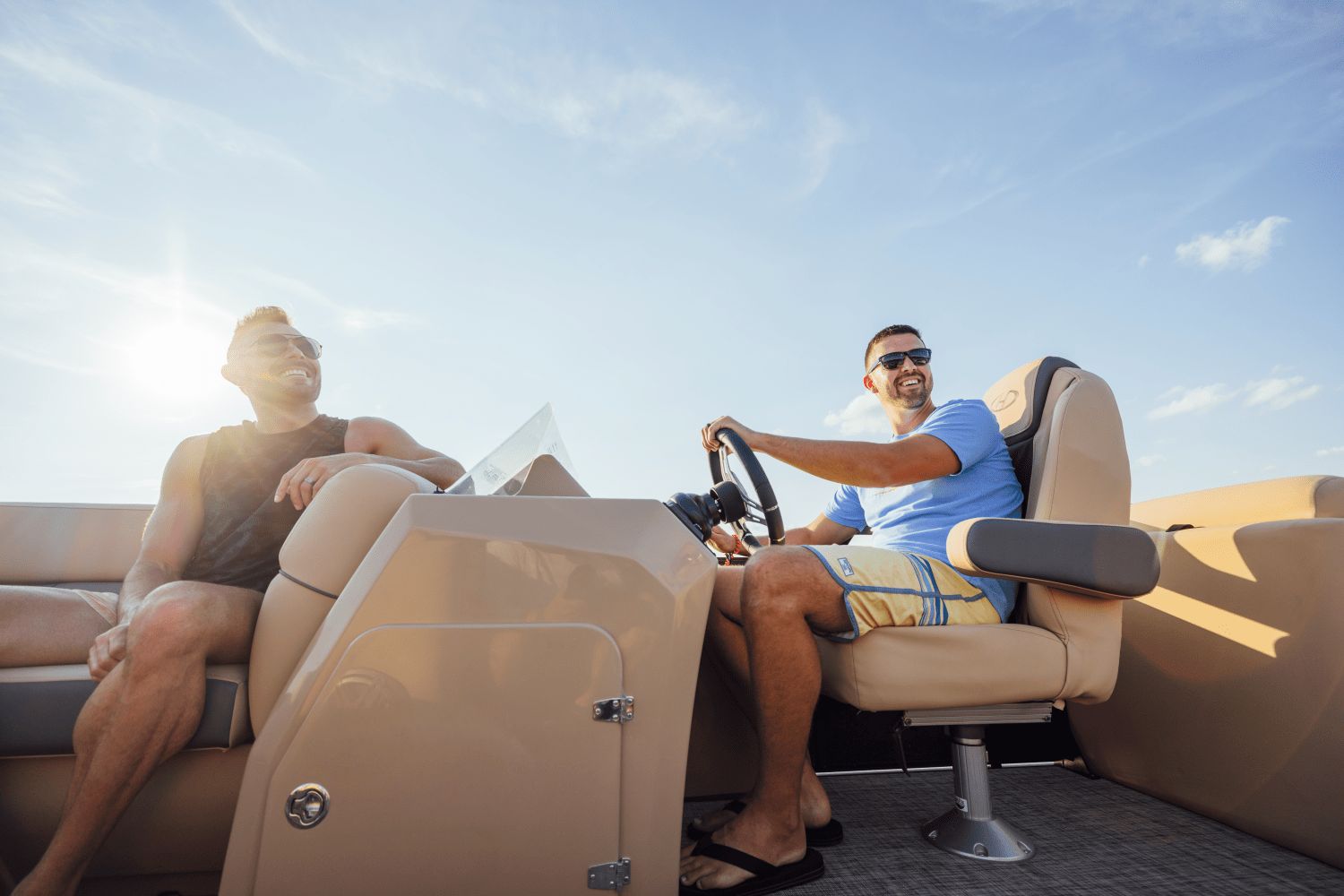 Two men sit on a Harris Cruiser 230 boat, enjoying the sunshine.