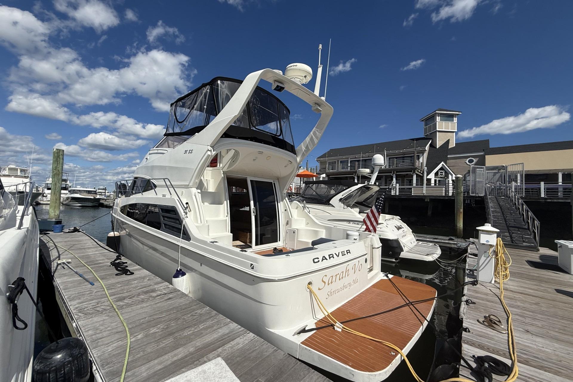 2006 Carver 38 Super Sport yacht docked at marina under blue sky.