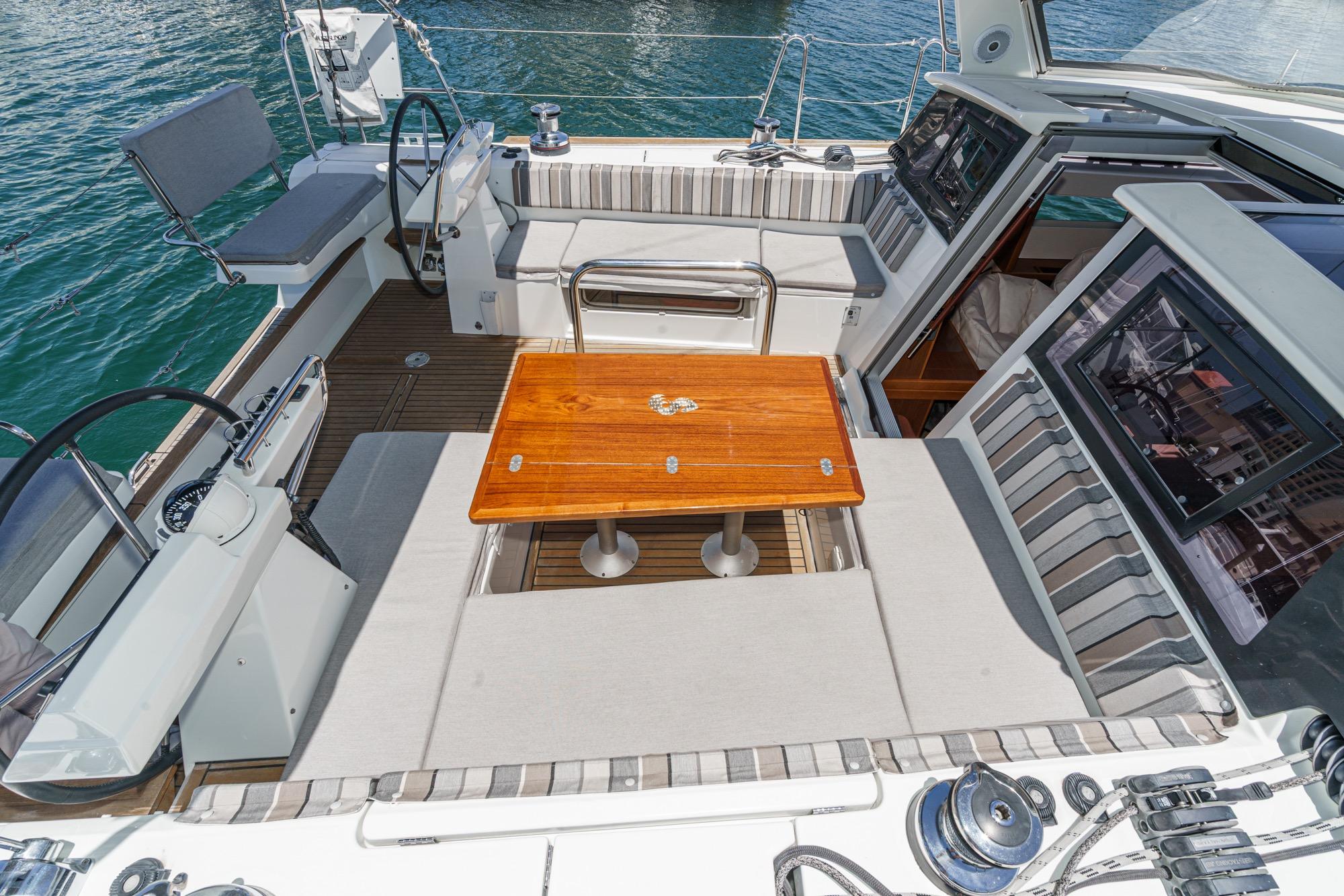 2017 Beneteau Sense 50 yacht cockpit with wooden table and striped seating.