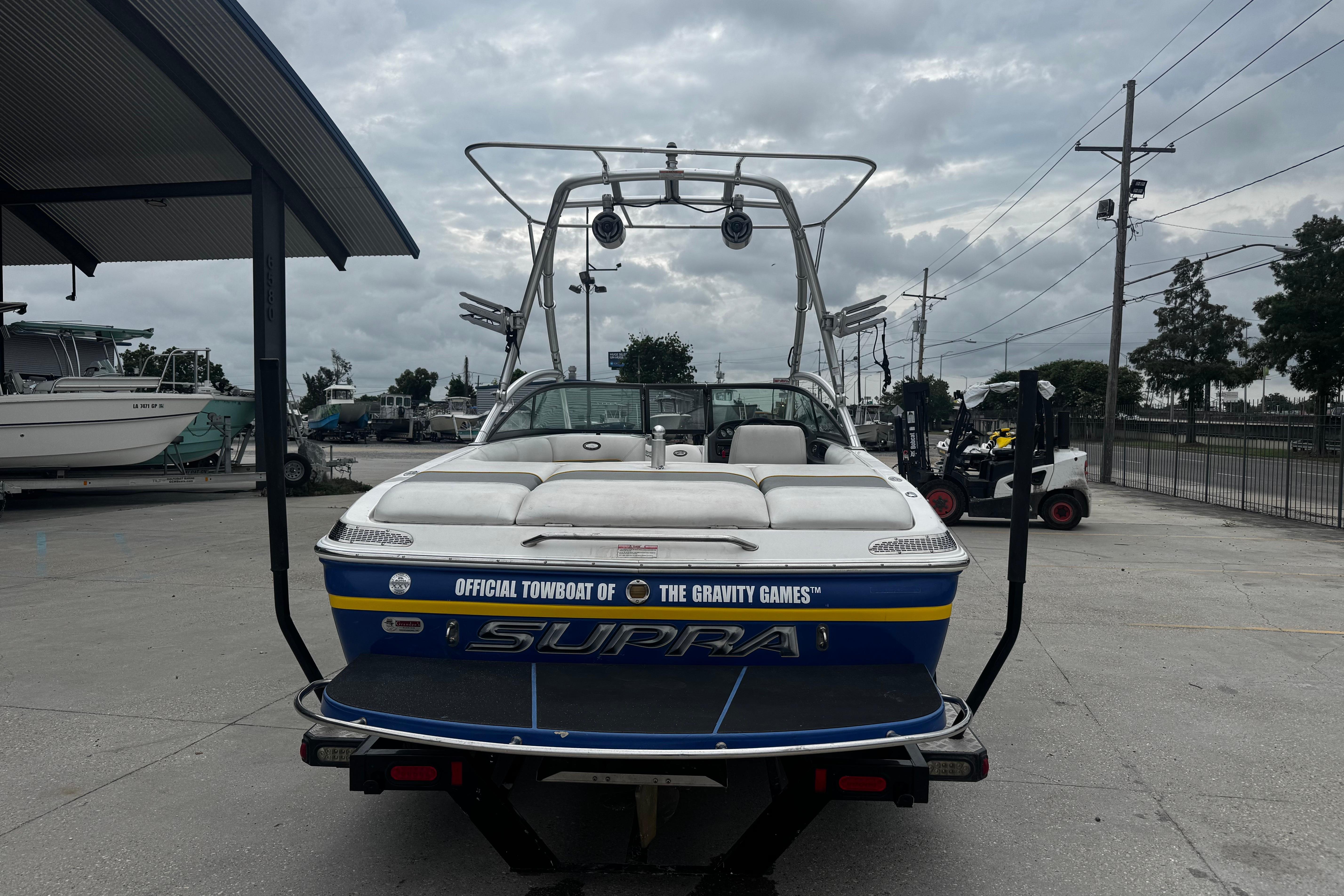 2006 Supra Launch 22 SSV boat on trailer, overcast sky, marina background.