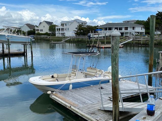 A 2022 Carolina Skiff 21 Ultra Elite docked in a calm residential area.