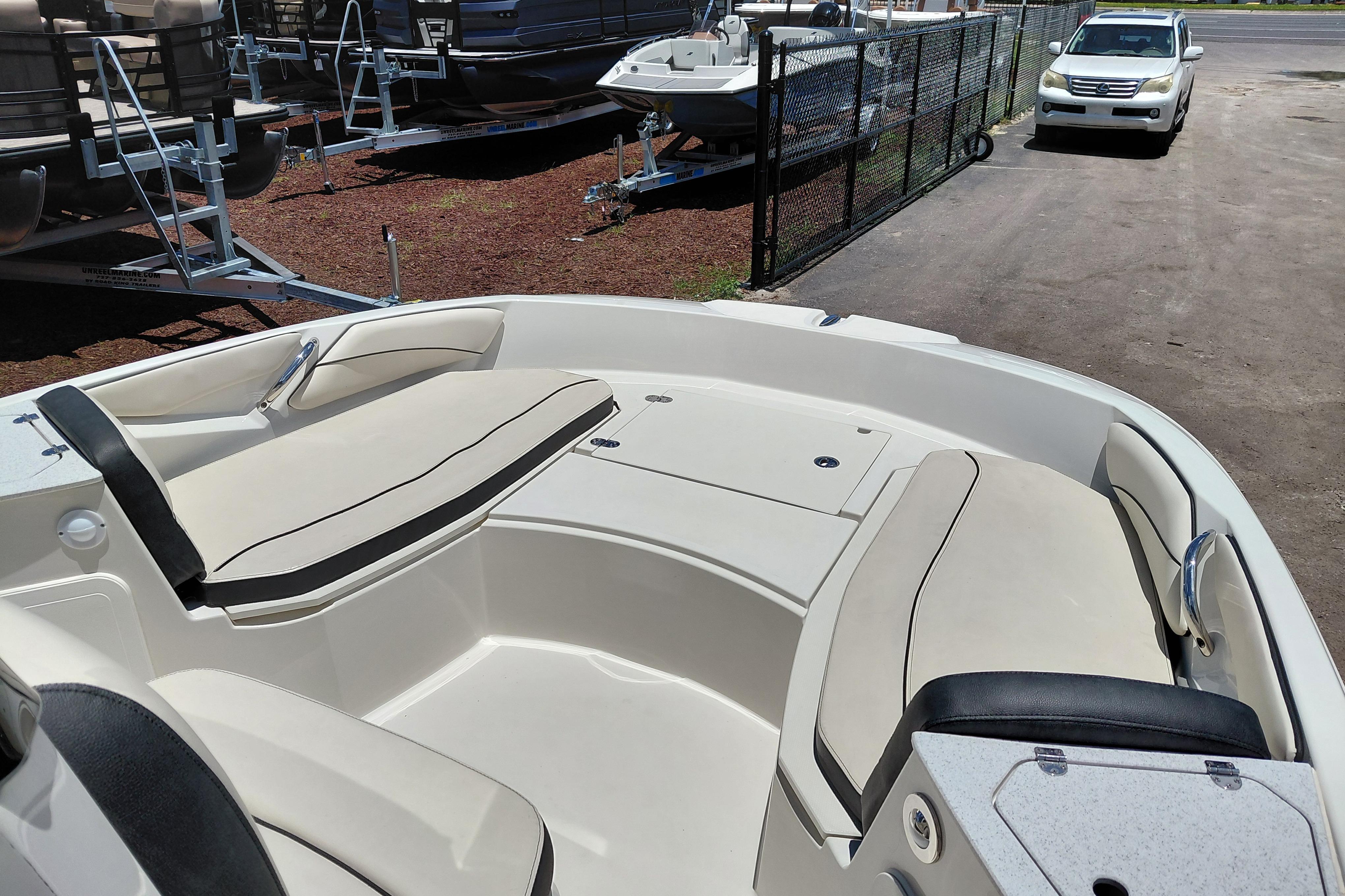 2023 Stingray 206 CC boat interior with beige seating, parked near trailers.