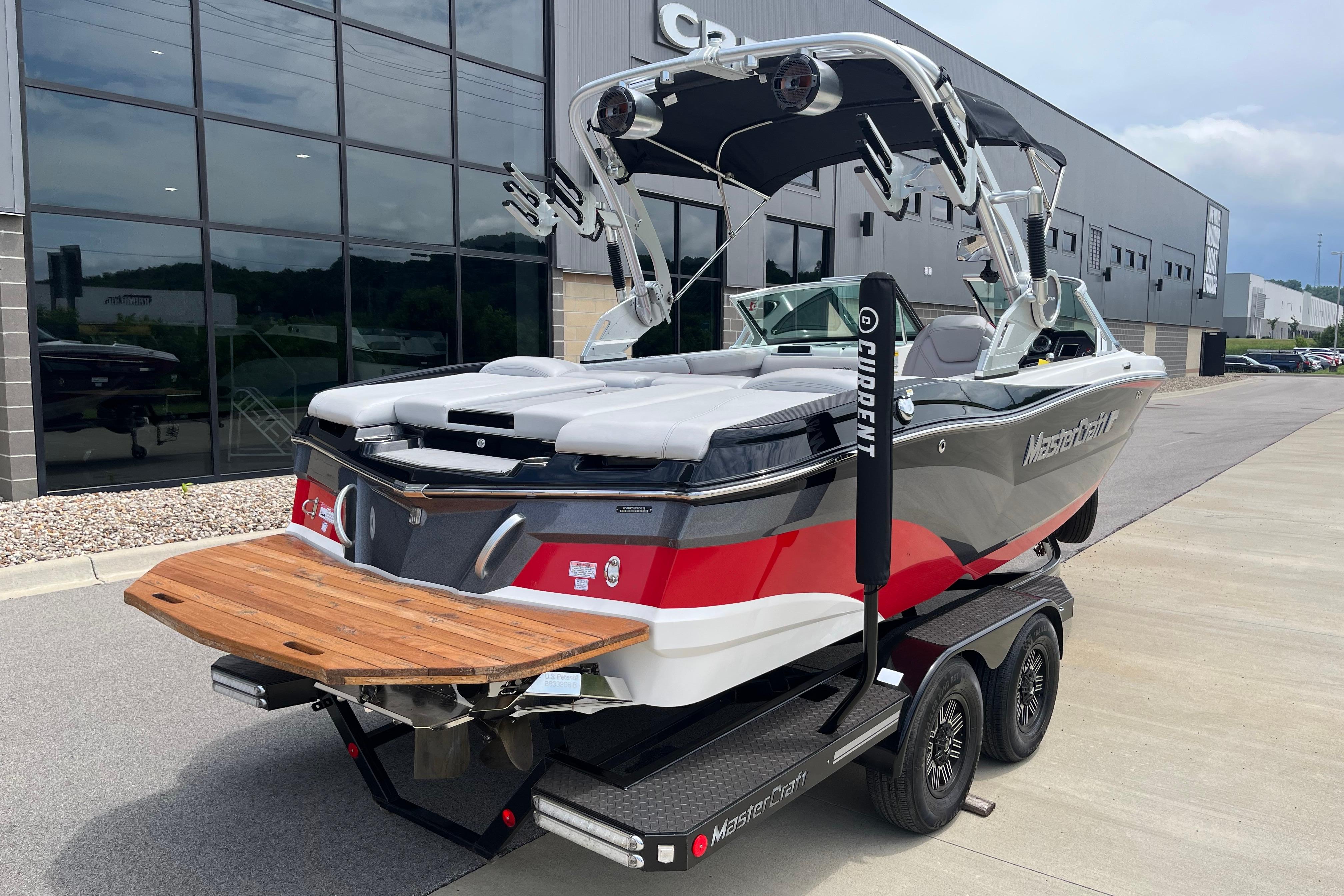 2019 MasterCraft XT20 boat on trailer, parked outside a modern building.