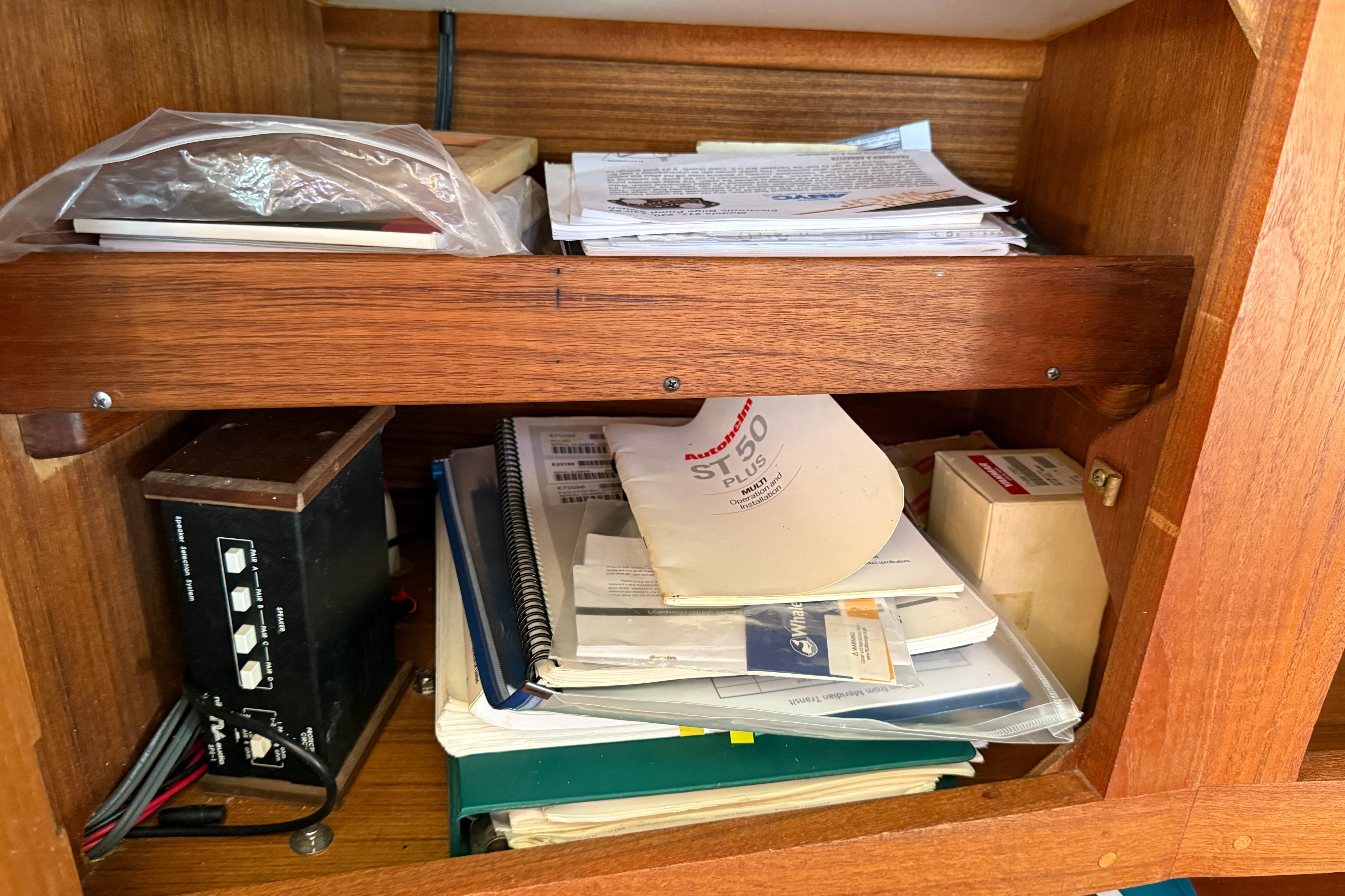 Wooden shelf with manuals, papers, and electronic equipment in a 1997 Tartan 3800.