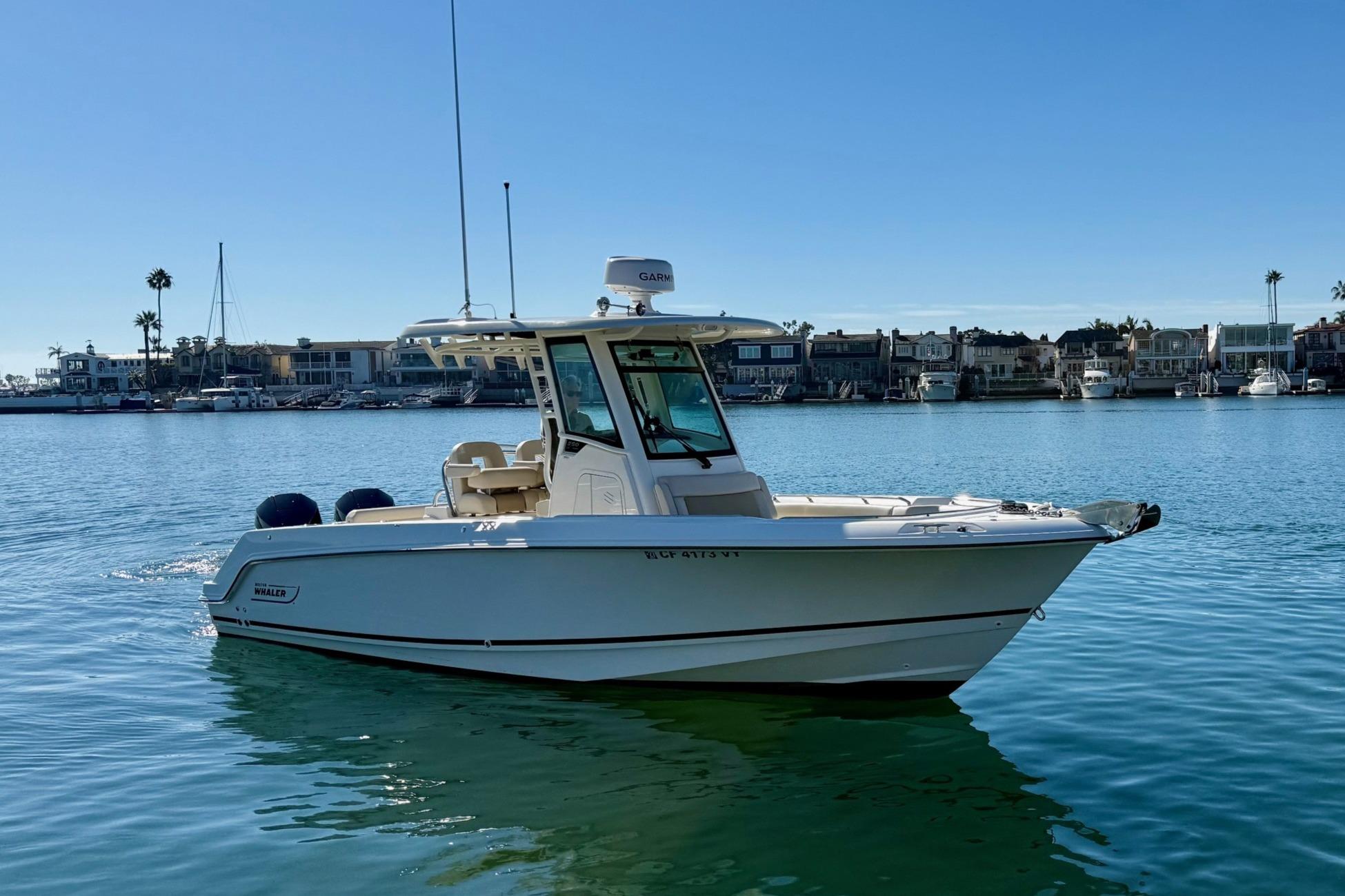 2025 Boston Whaler 250 Outrage boat on calm water, with coastal background.