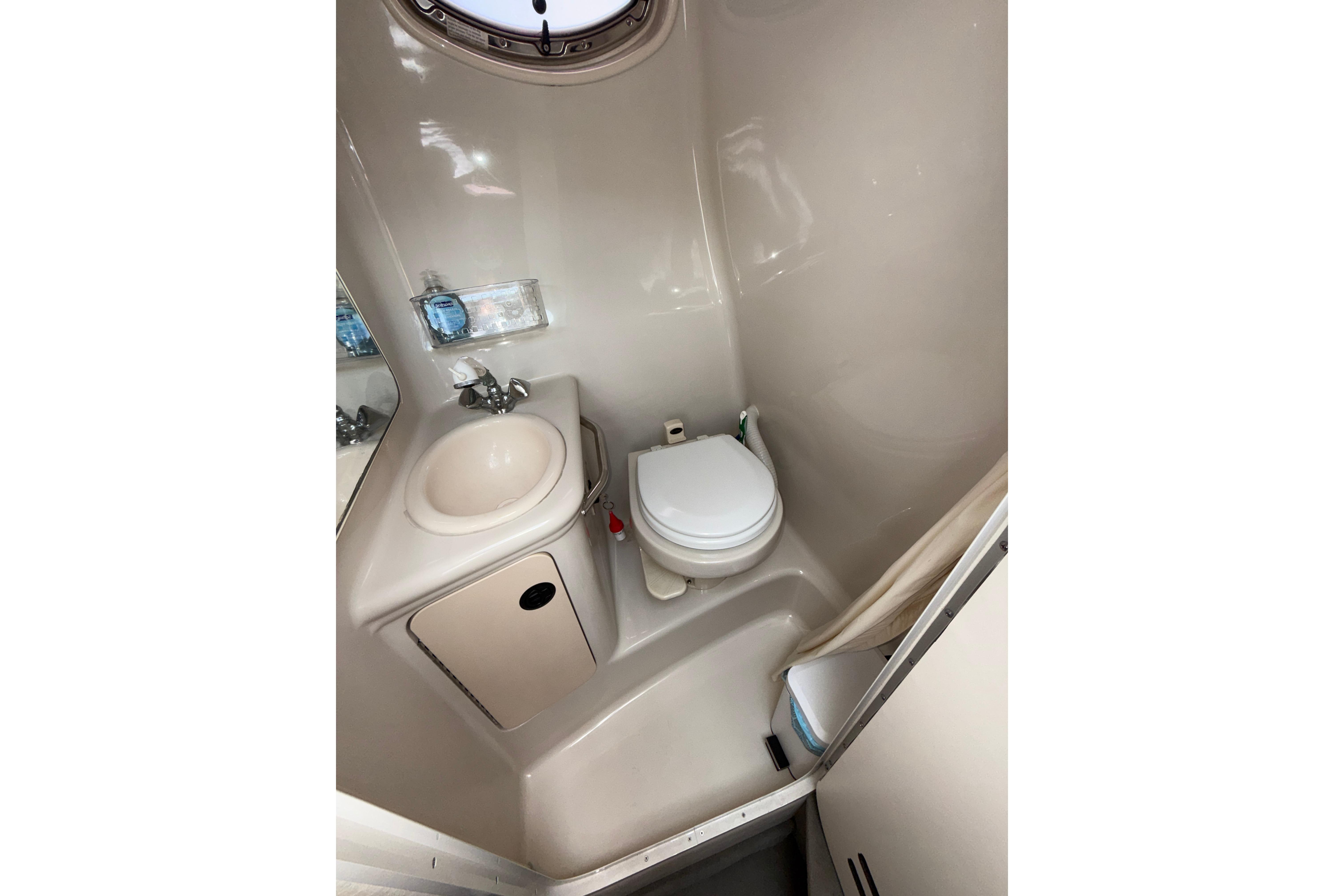 Compact bathroom in 2004 Sea Ray 240 Sundancer boat, featuring sink and toilet.
