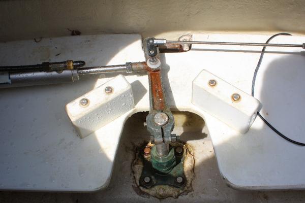 Close-up of a steering mechanism on a boat, featuring metal rods and fittings.