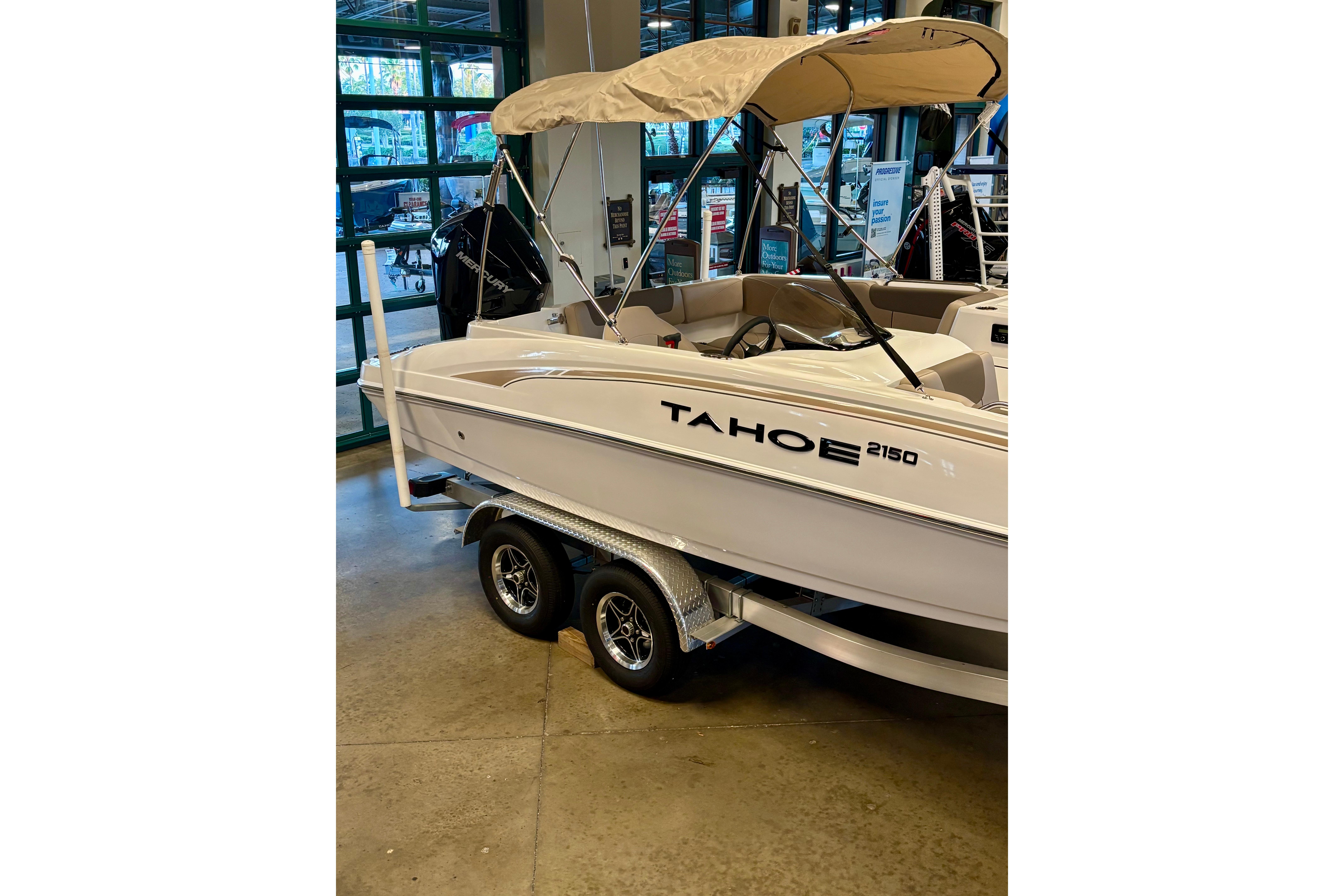 2026 Tahoe 2150 boat with canopy on trailer in showroom.
