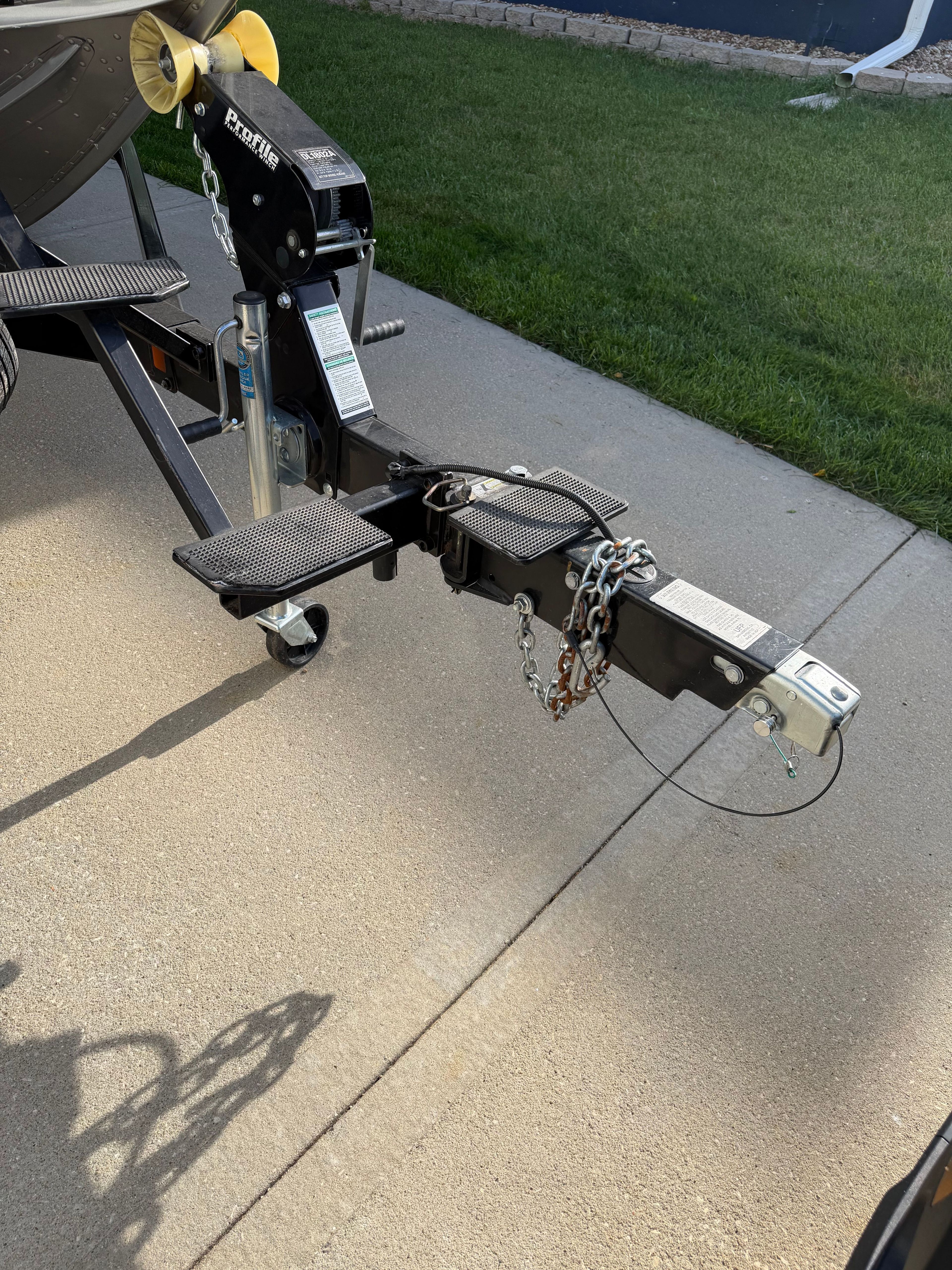 Trailer hitch of a 2017 Lund Pro v 1975 boat on concrete surface.
