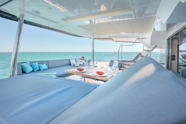 Luxurious Privilege Signature 650 yacht deck with ocean view, featuring elegant seating and dining area.