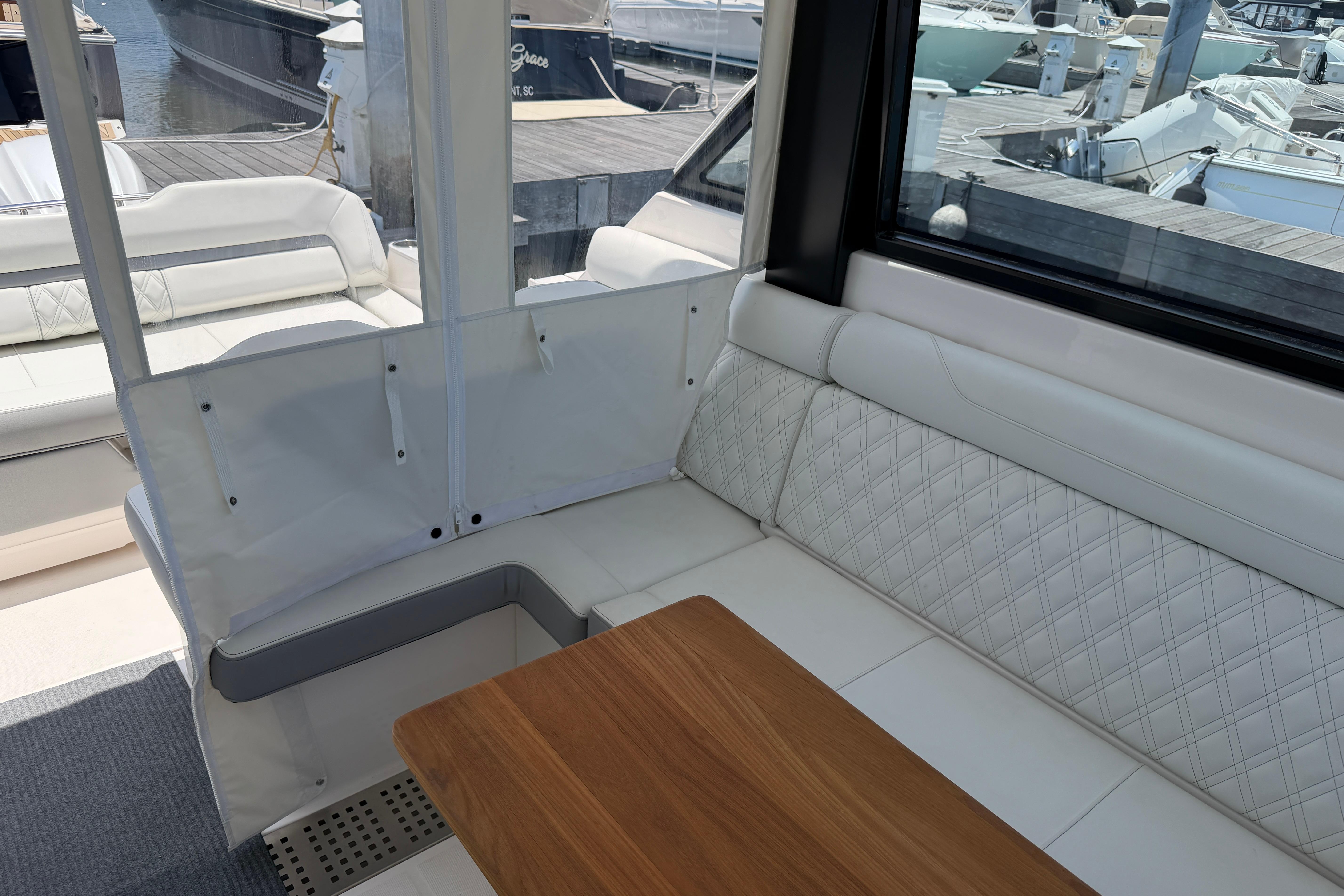 Luxurious interior of 2024 Regal 36 XO yacht with white seating and wooden table.