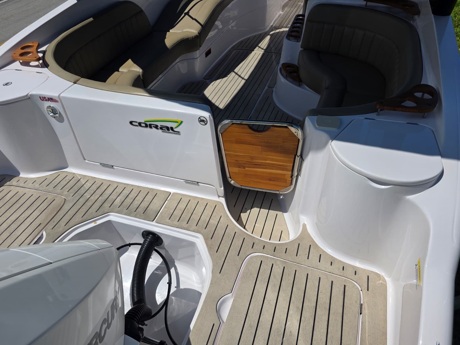 The image shows the cockpit of a Coral 26 boat with beige seating and wood accents.