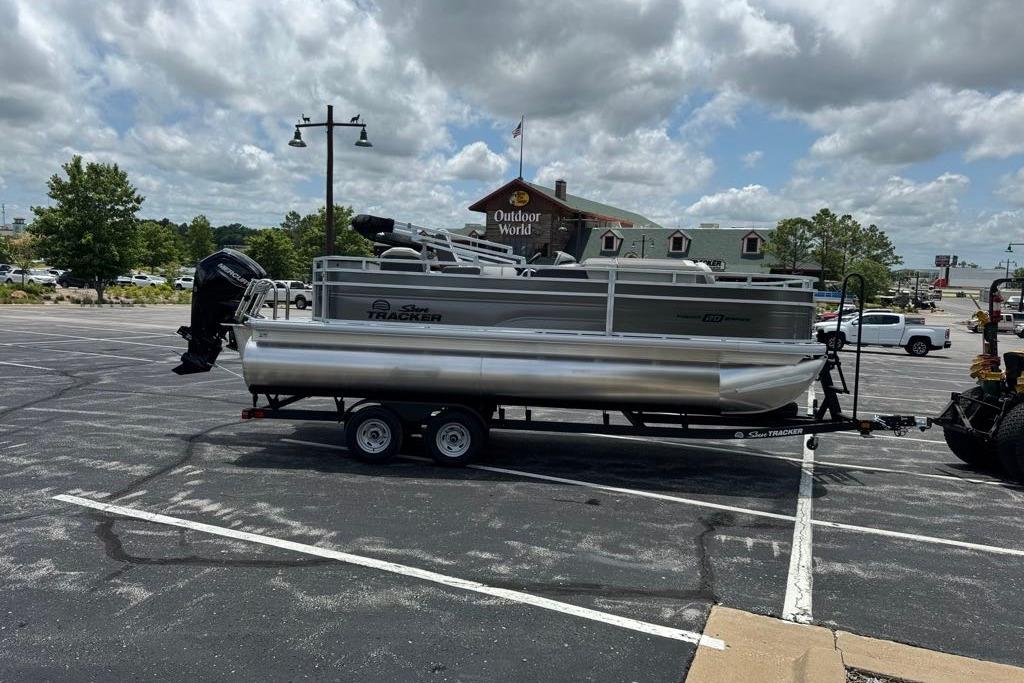 2026 Sun Tracker Fishin' Barge 20 DLX pontoon boat on trailer in parking lot.