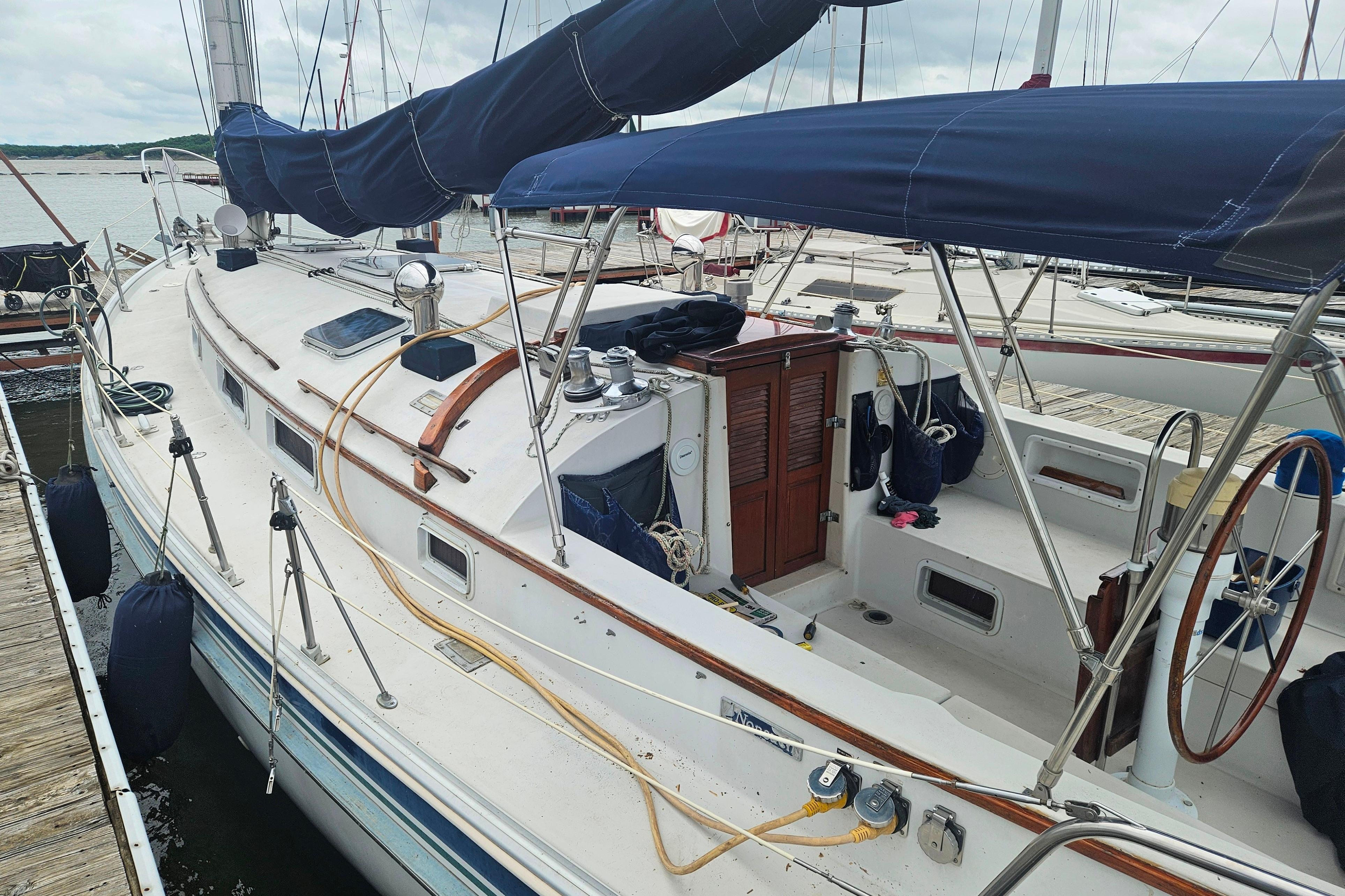 1989 Nonsuch 36 sailboat docked, featuring a spacious deck and blue canvas covers.