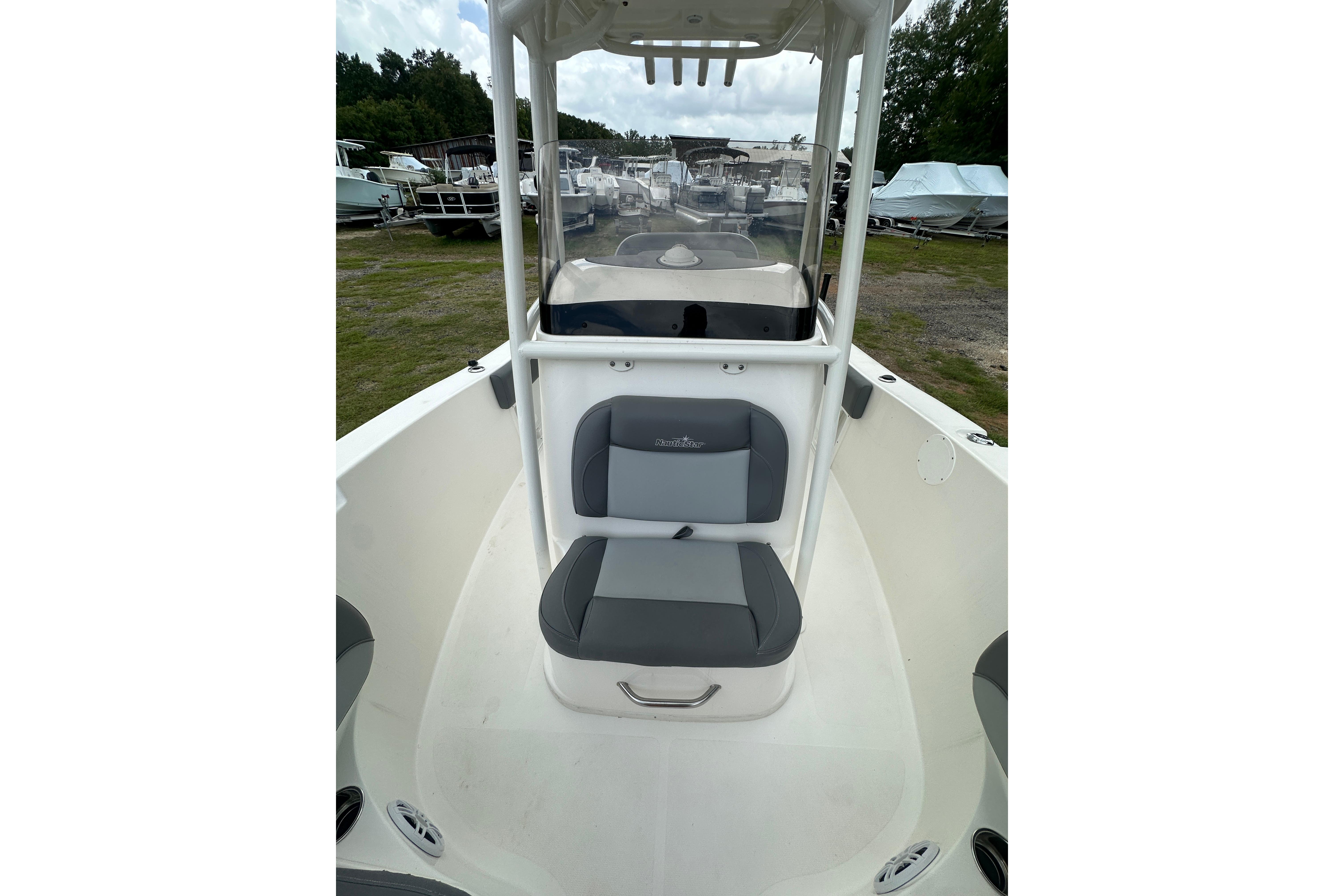 2023 NauticStar 2102 Legacy boat interior with seating and console, parked outdoors.