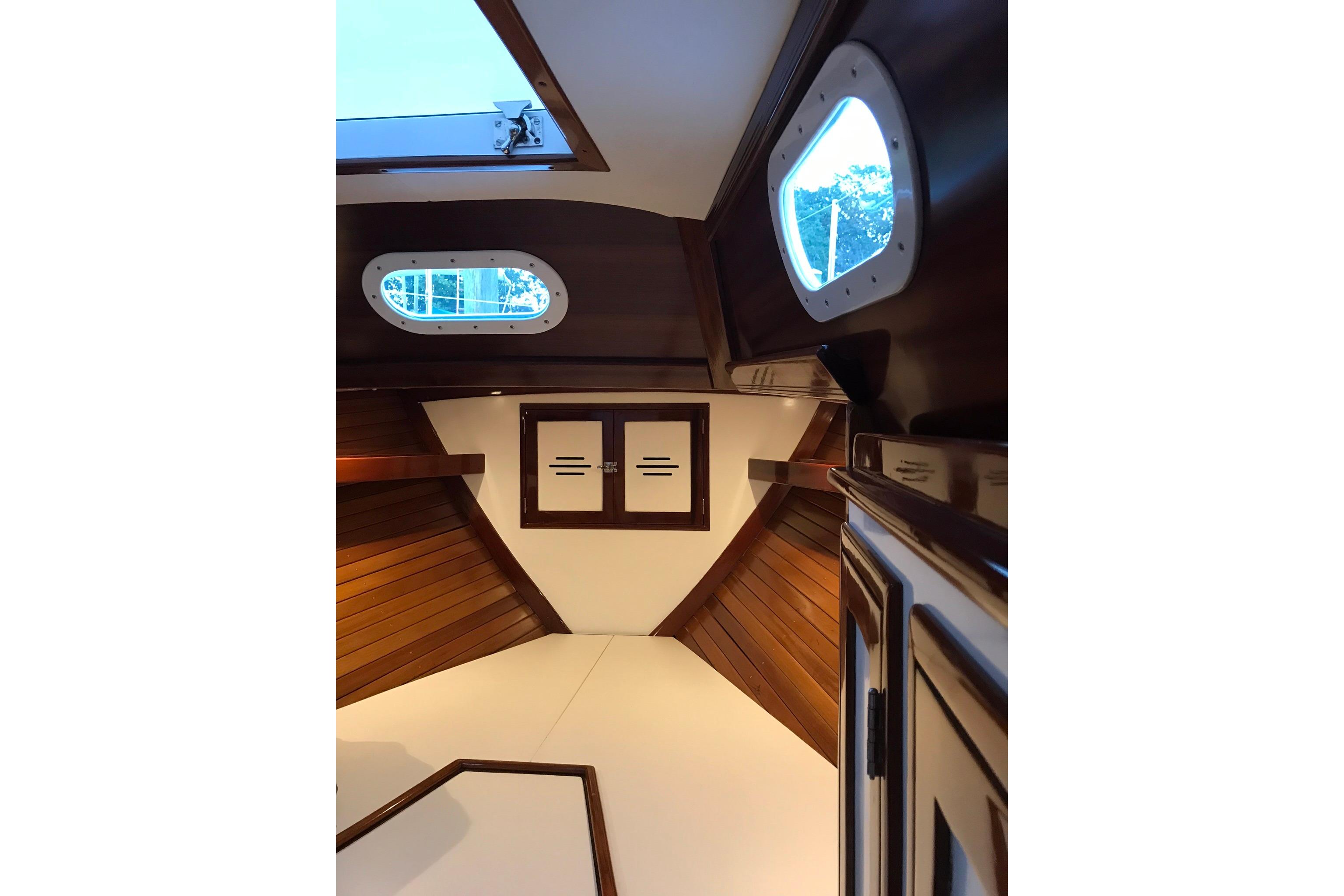 Interior of a 1970 Hinckley Bermuda 40 sailboat, featuring wooden paneling and portholes.