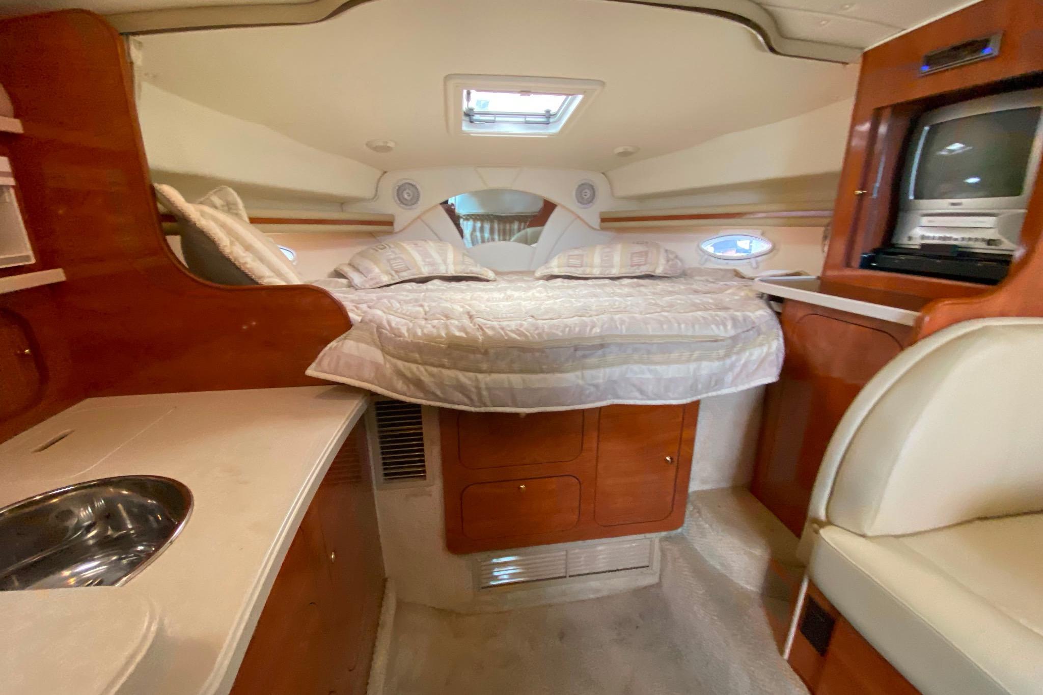 Interior of 2003 Rinker Fiesta Vee 342 boat with cozy bed and kitchenette.