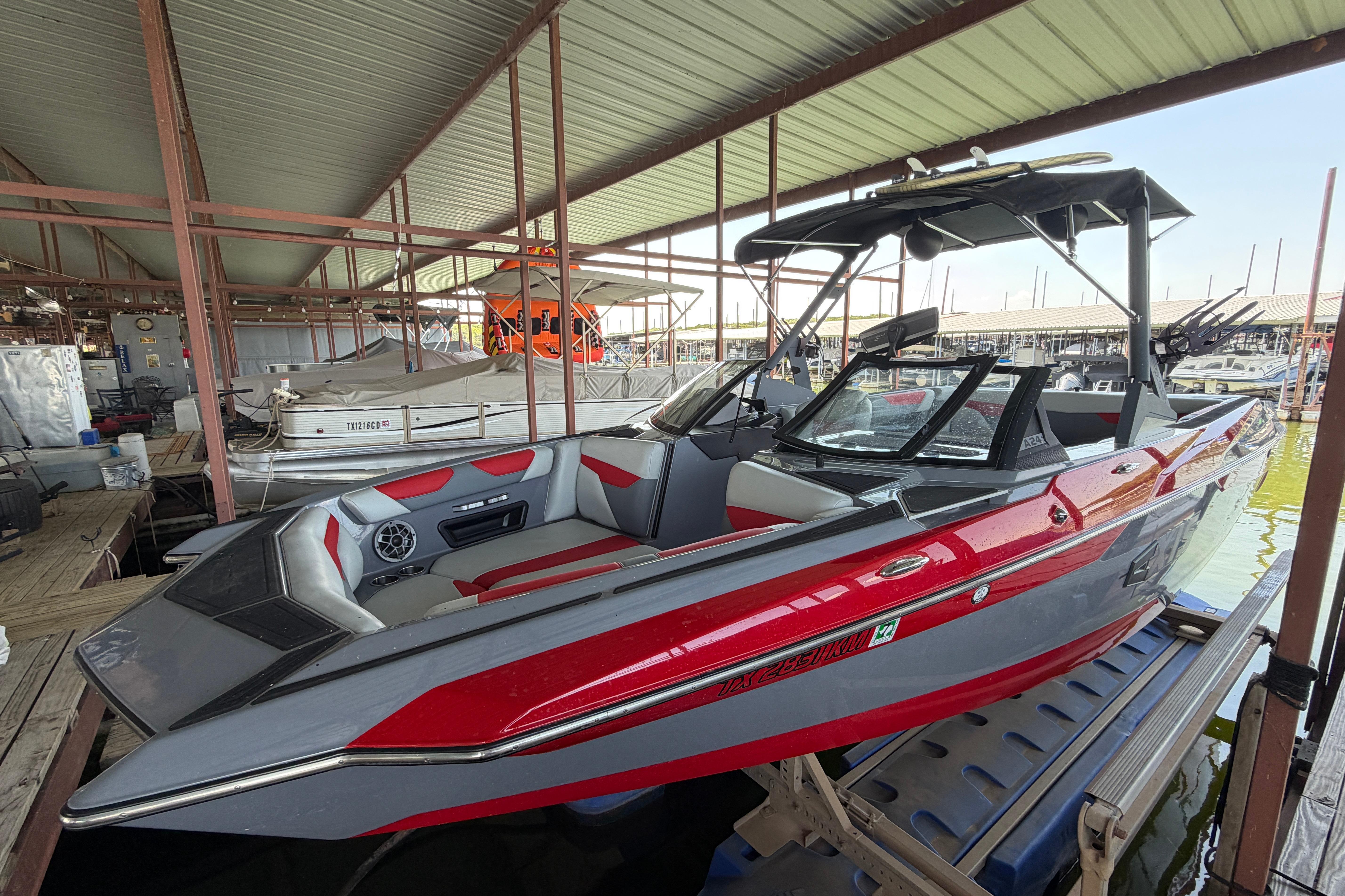 2021 Axis A24 boat in dock, featuring sleek red and gray design under a covered marina.