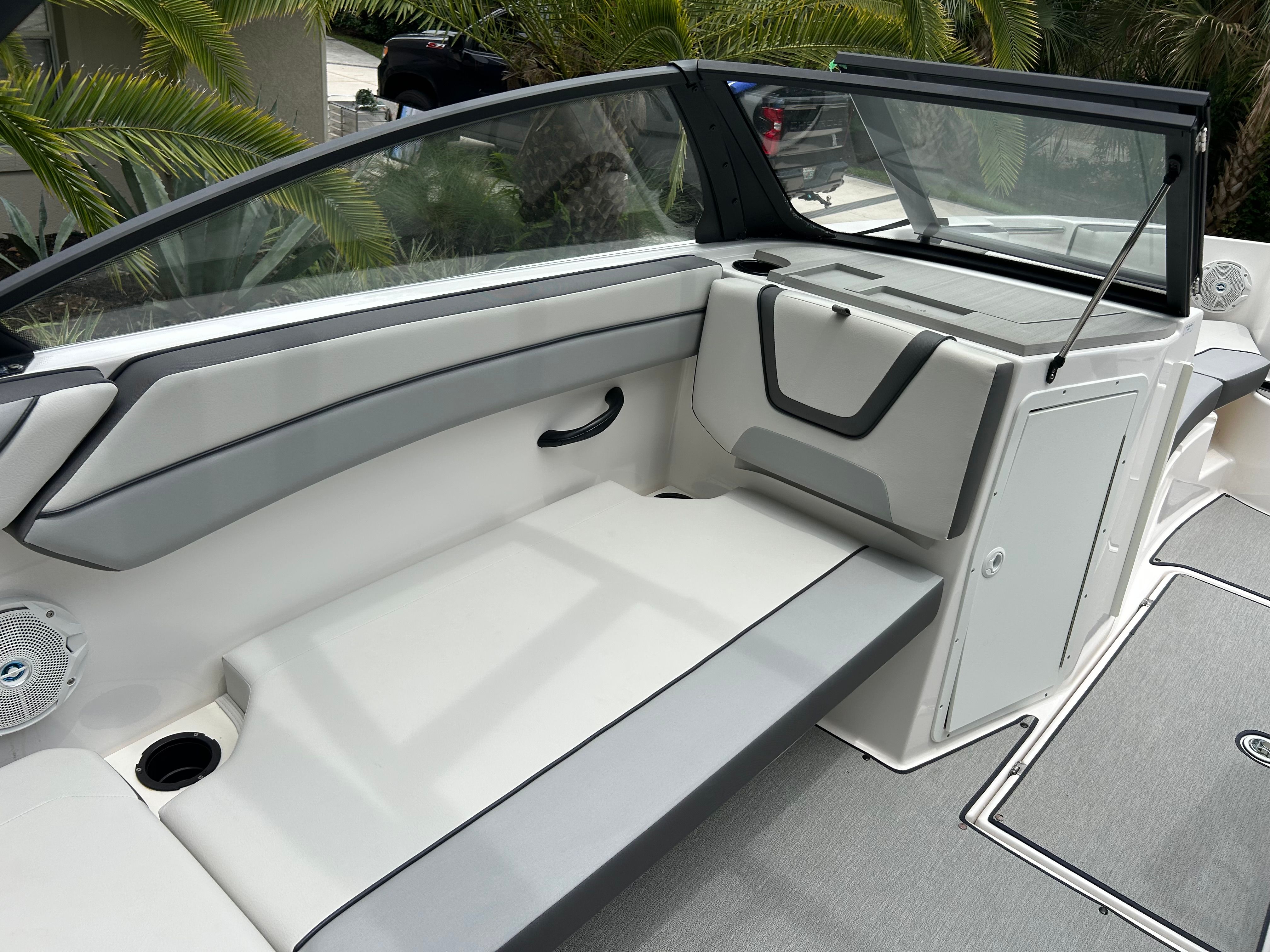 Interior view of a modern boat with gray and white seating and an open storage compartment.