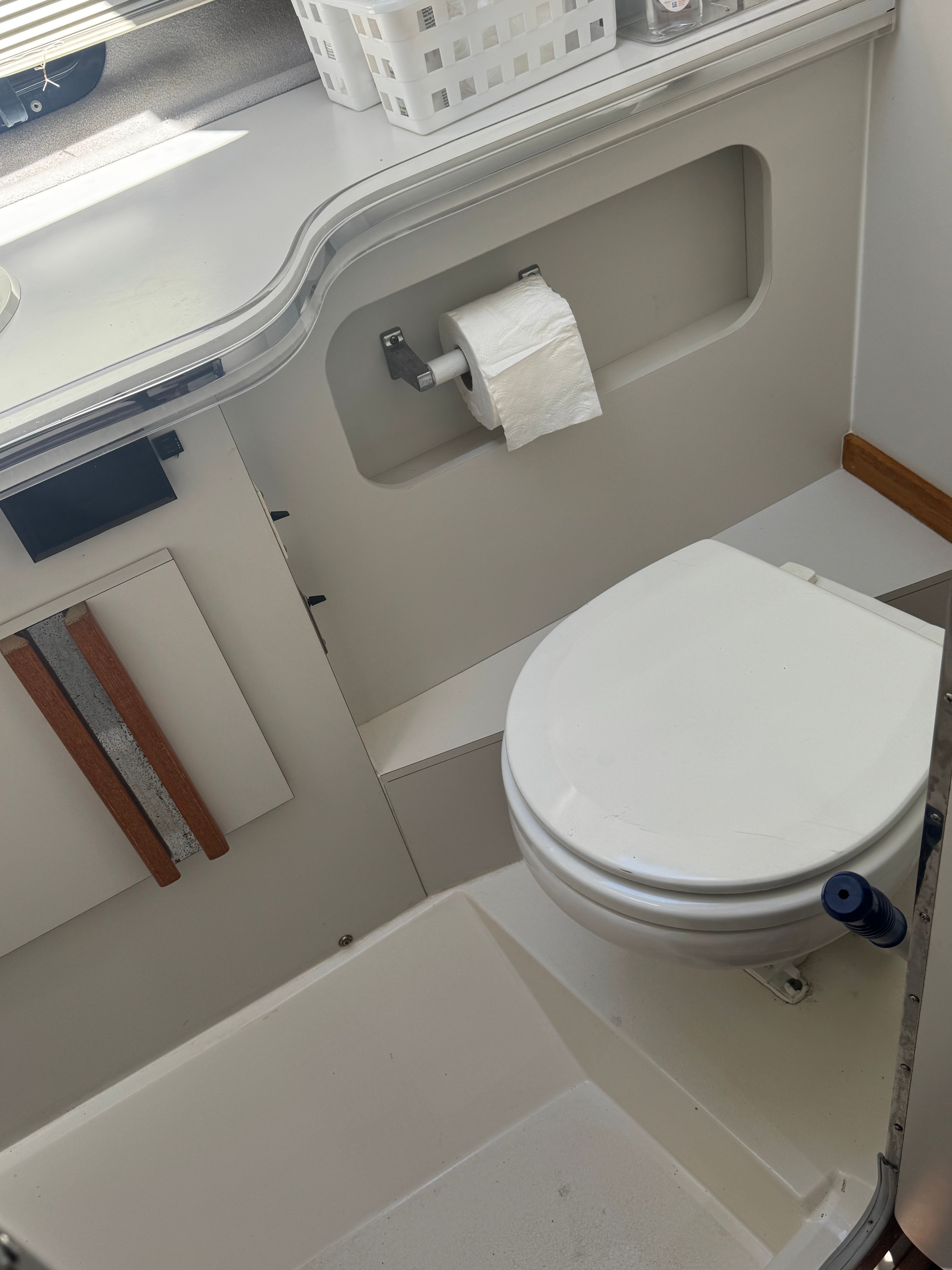 The image shows a boat bathroom with a toilet and a paper holder.