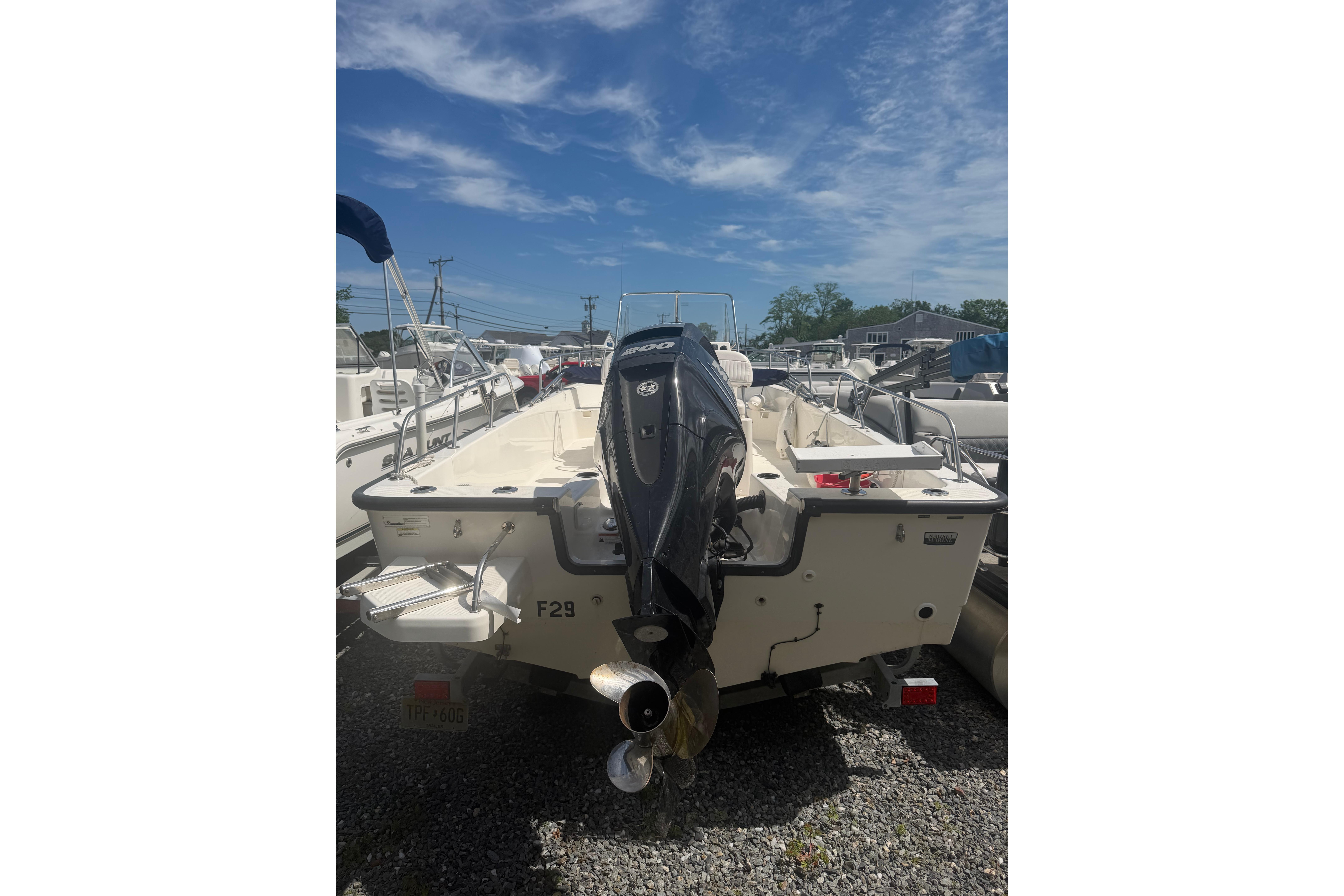 2015 Boston Whaler 210 Montauk boat with outboard motor, parked on gravel.