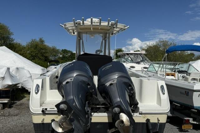 2006 Sailfish 2660 CC boat with dual outboard motors, docked under clear blue sky.