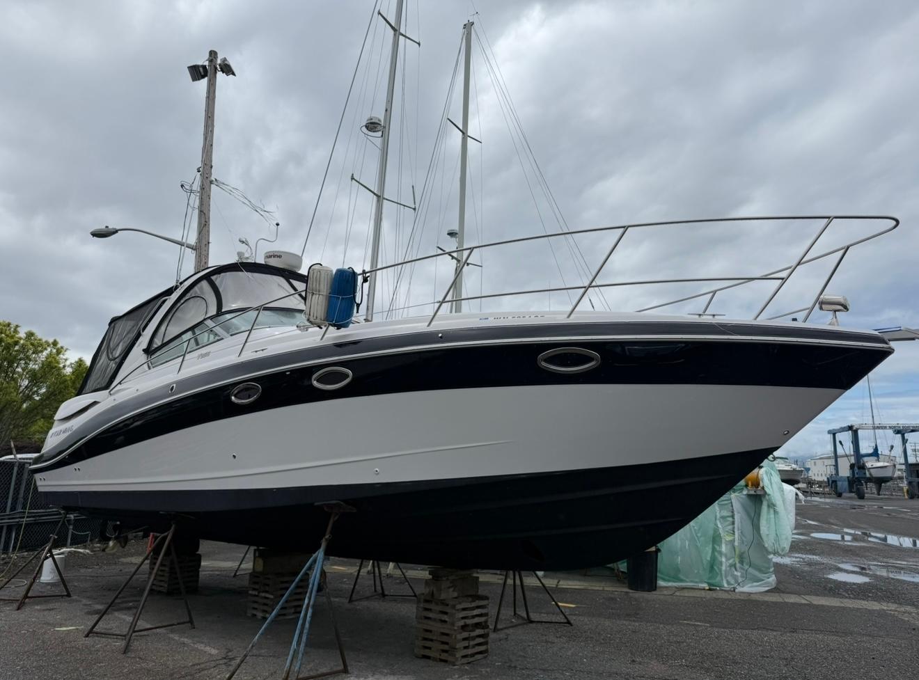 2008 Four Winns V358 boat on stands, overcast sky, marina background.