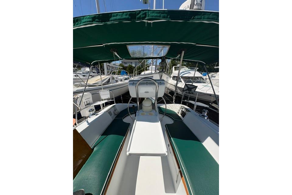 Cockpit view of a 2000 Beneteau Oceanis 321 sailboat with green canopy and seating.