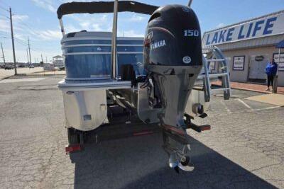 2026 SunCatcher Select 322RC pontoon boat with Yamaha 150 engine, parked near "Lake Life" store.