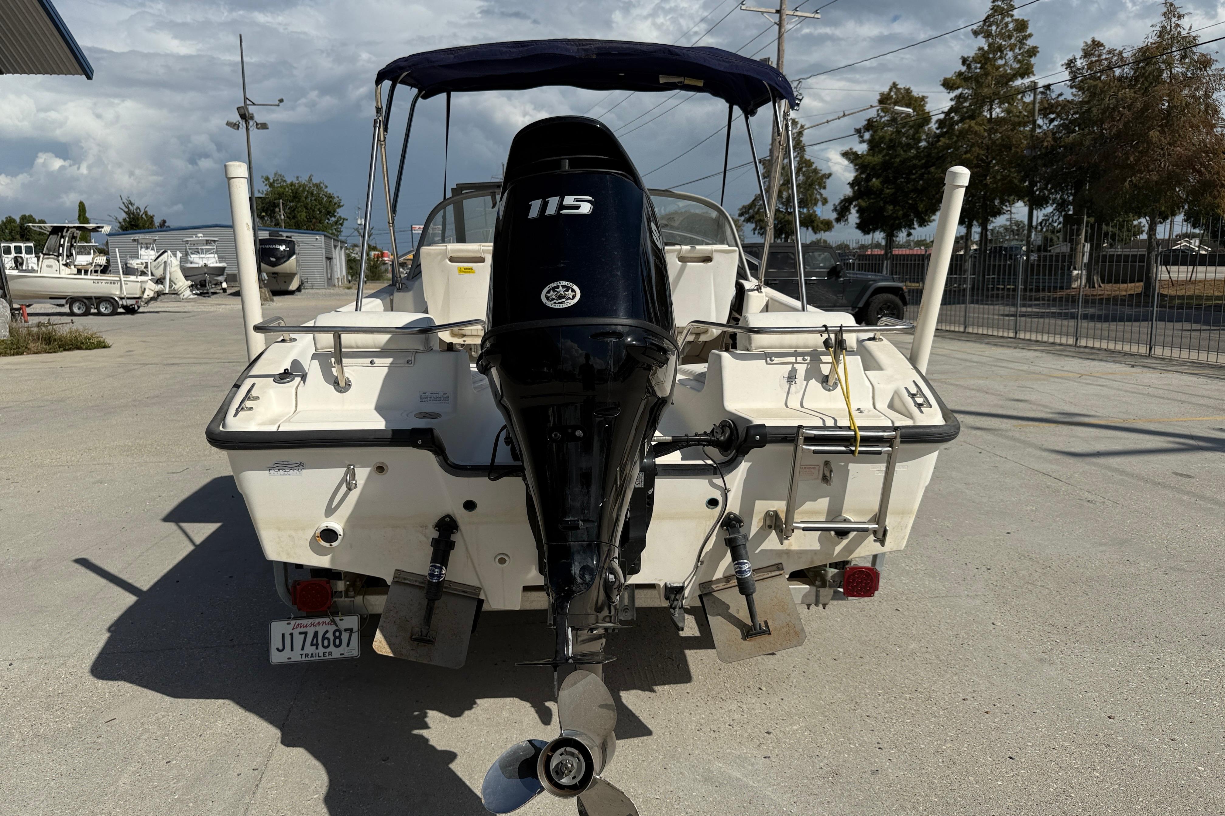 2002 Boston Whaler Ventura 160 boat with 115 HP engine, parked outdoors.