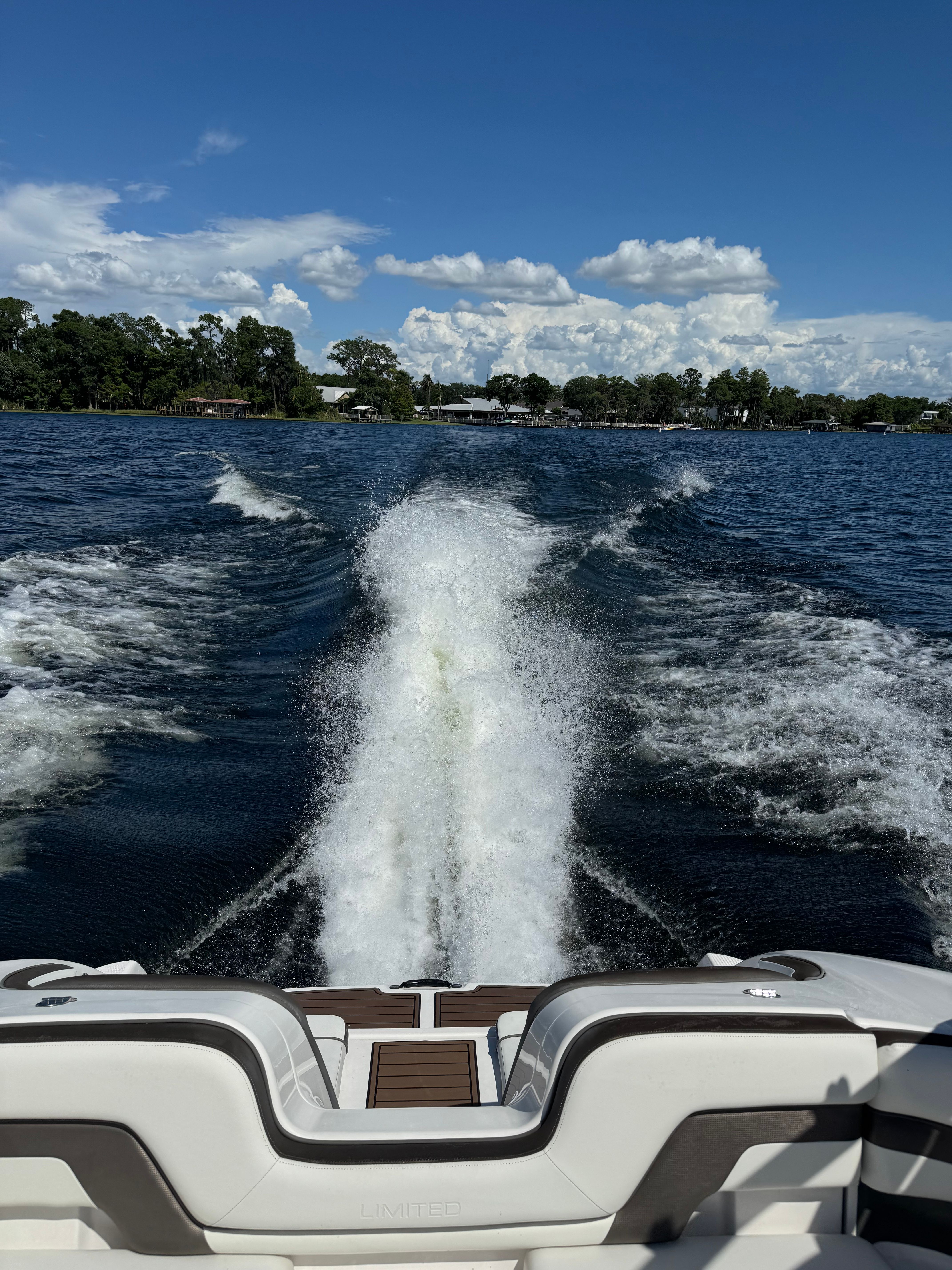 A 2015 Yamaha 242 Limited S boat cruising on a lake, leaving a splashing wake.