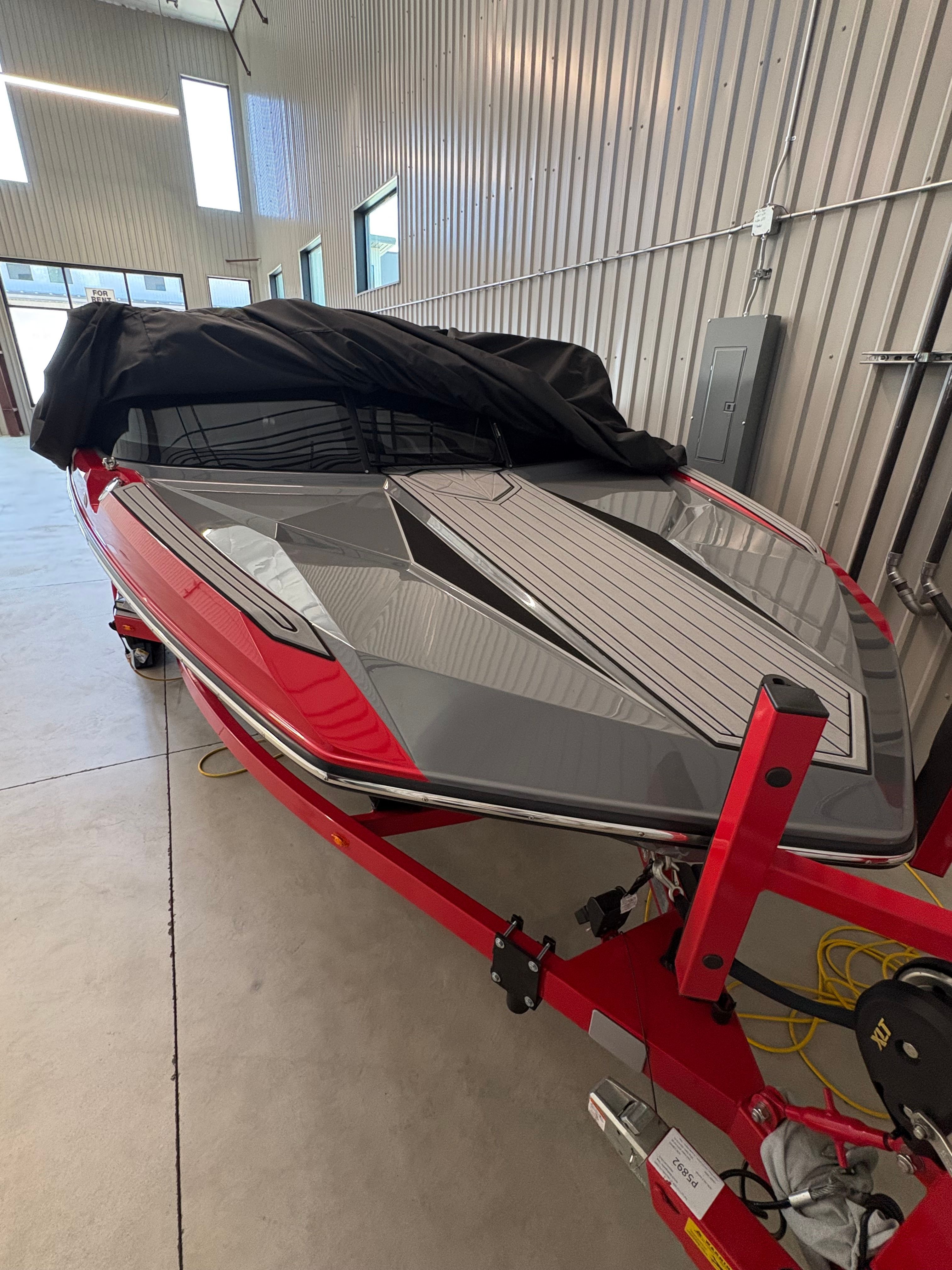A 2023 Ski Nautique boat in a warehouse, partially covered with a black tarp.