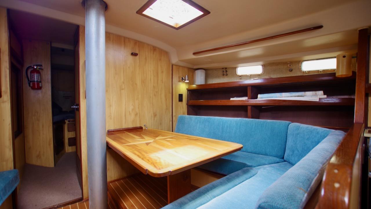 Interior of 1981 Morgan Out Island 41 sailboat with wooden table and blue seating.
