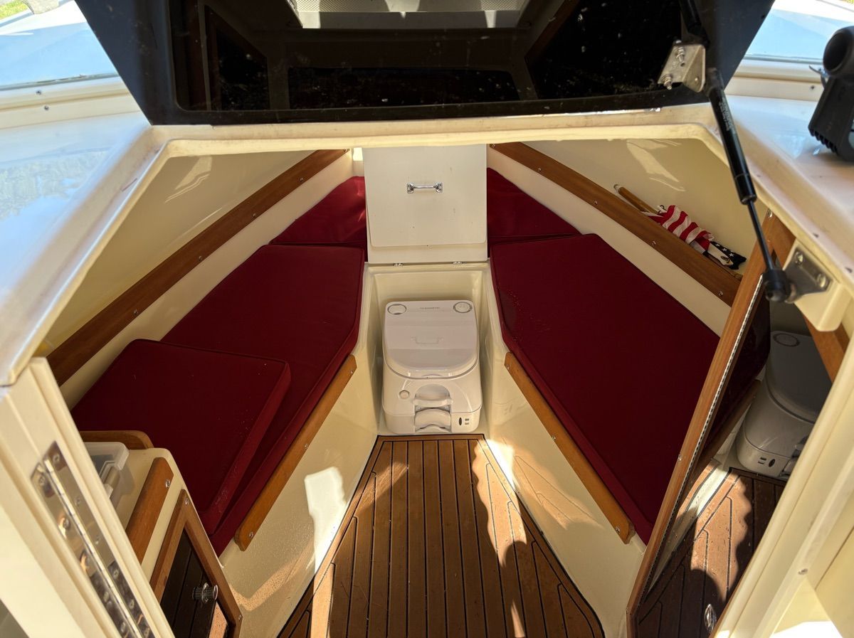 Interior of a 2018 Seaway Seafarer 21 with red seating cushions and wooden flooring.