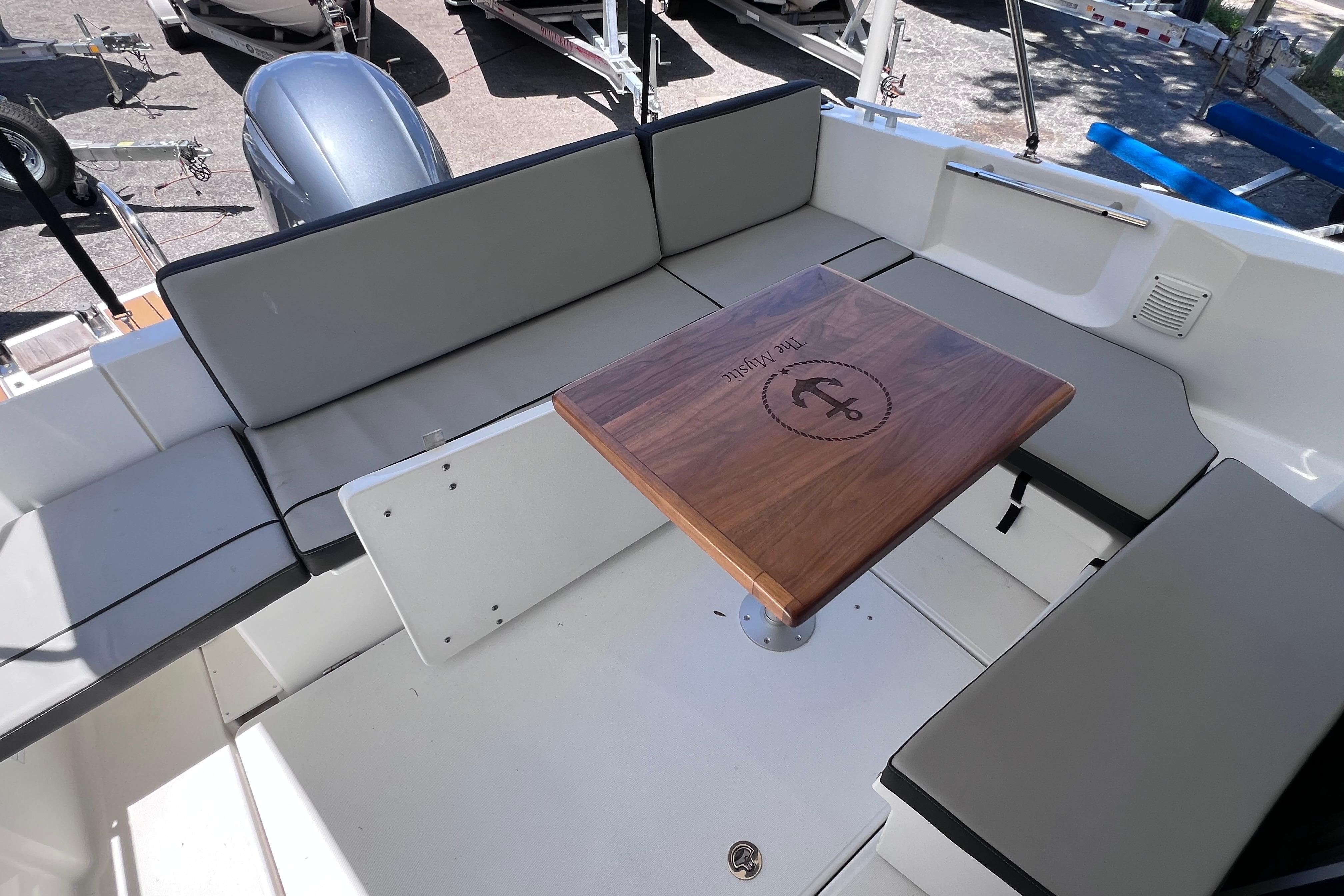 2021 Jeanneau NC Weekender 795 Series 2 boat interior with cushioned seating and wooden table.