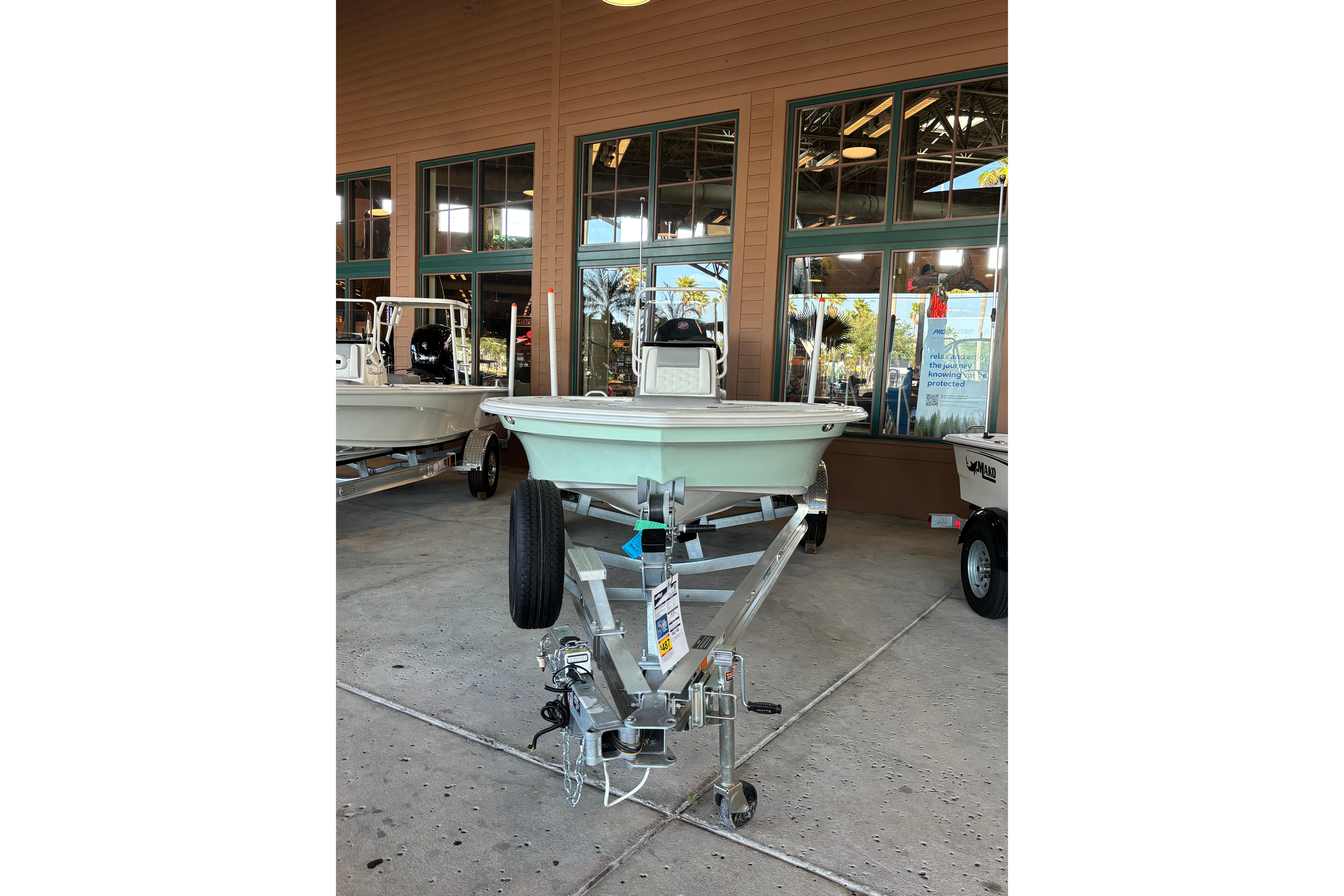 2026 Mako 18 Pro Skiff boat on trailer, displayed outside a showroom.