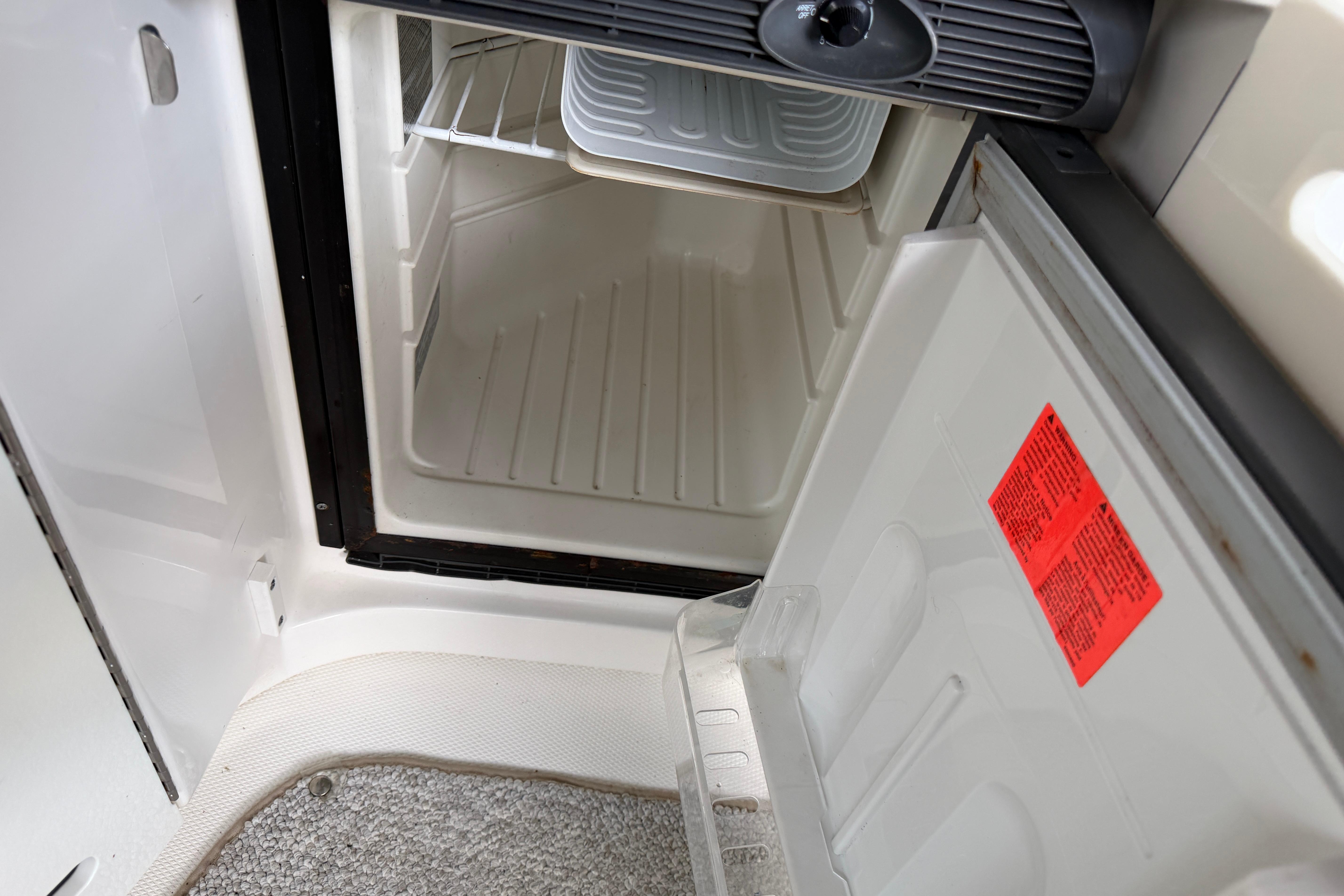 Open refrigerator inside a 2003 Sea Ray 290 Bowrider boat, showing interior shelves.