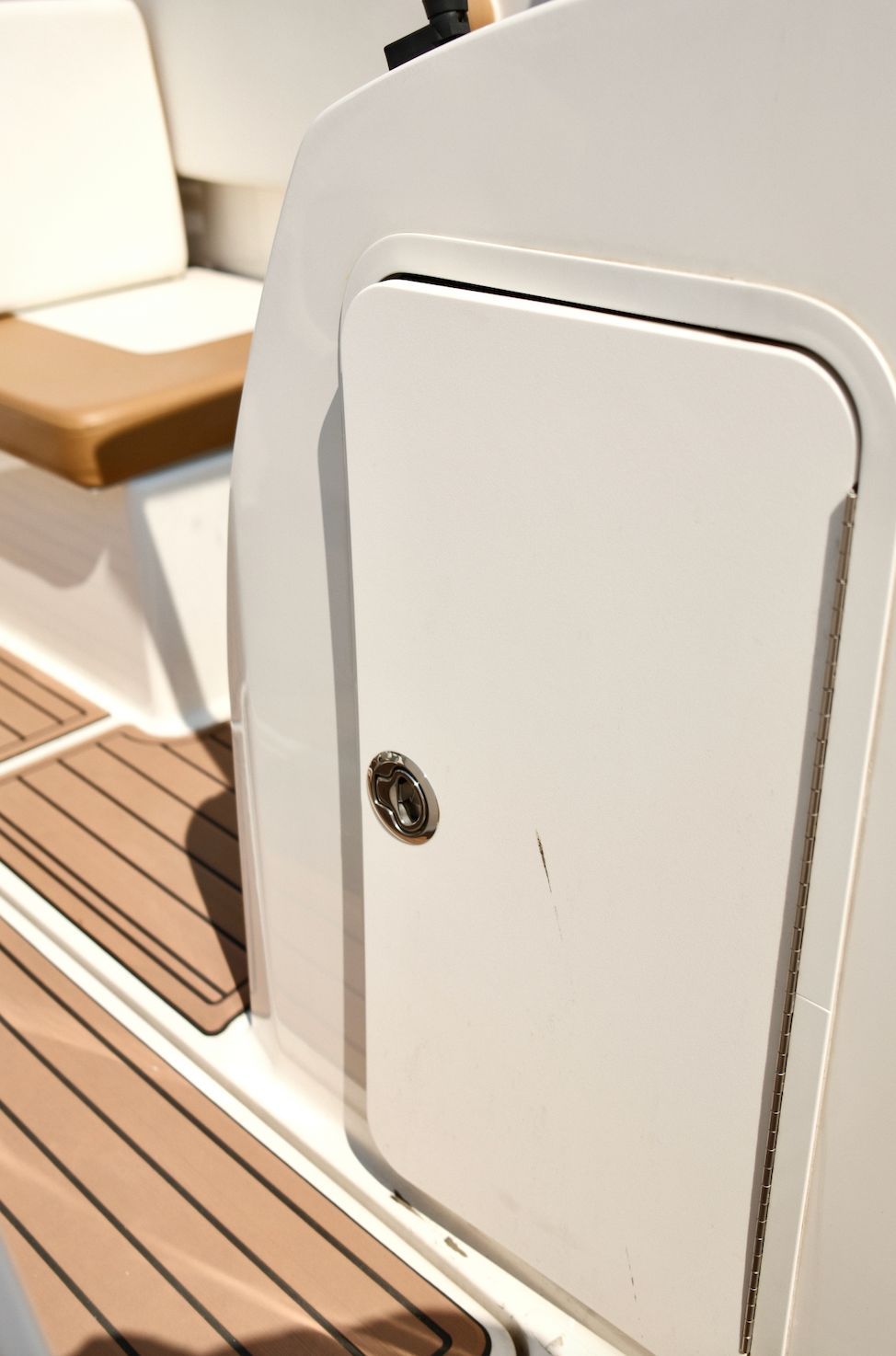 Close-up of a white storage compartment on a boat with brown flooring.