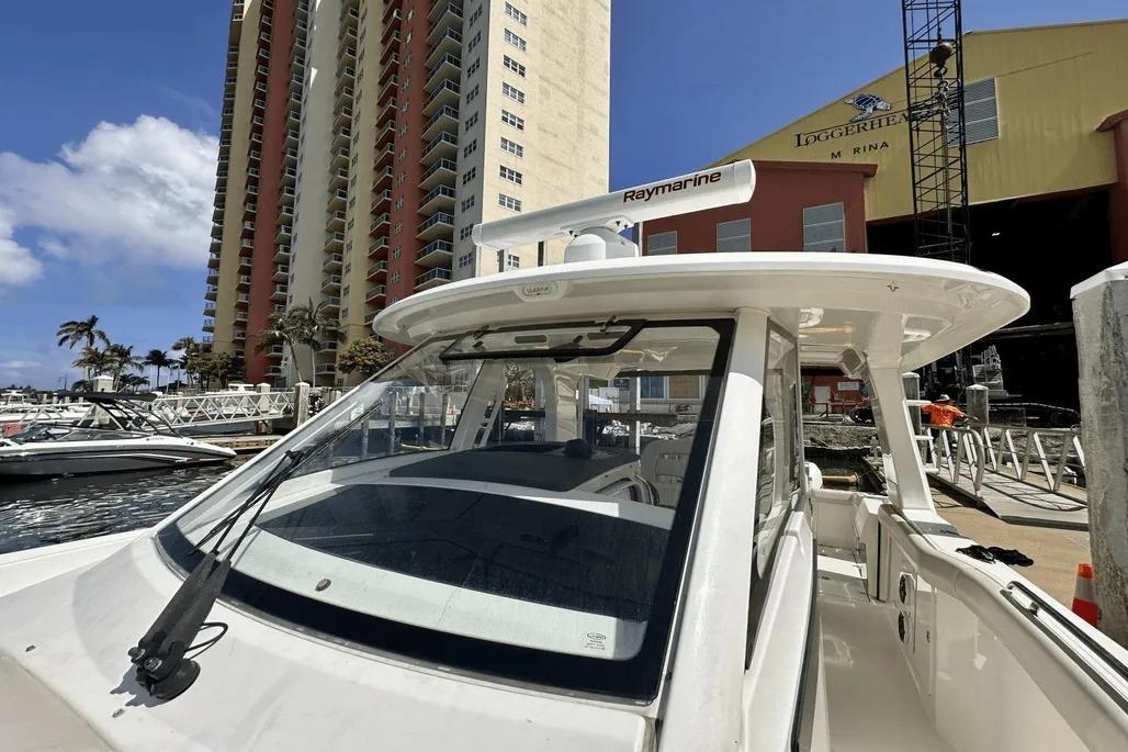 2019 Boston Whaler 350 Realm docked at marina with tall buildings in background.