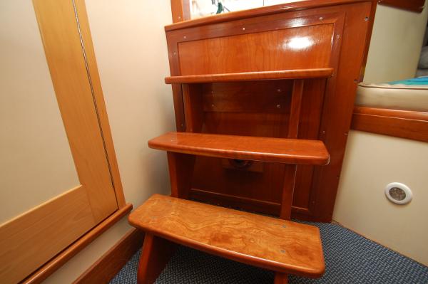 Wooden steps inside a boat, with carpeted floor and wooden walls.