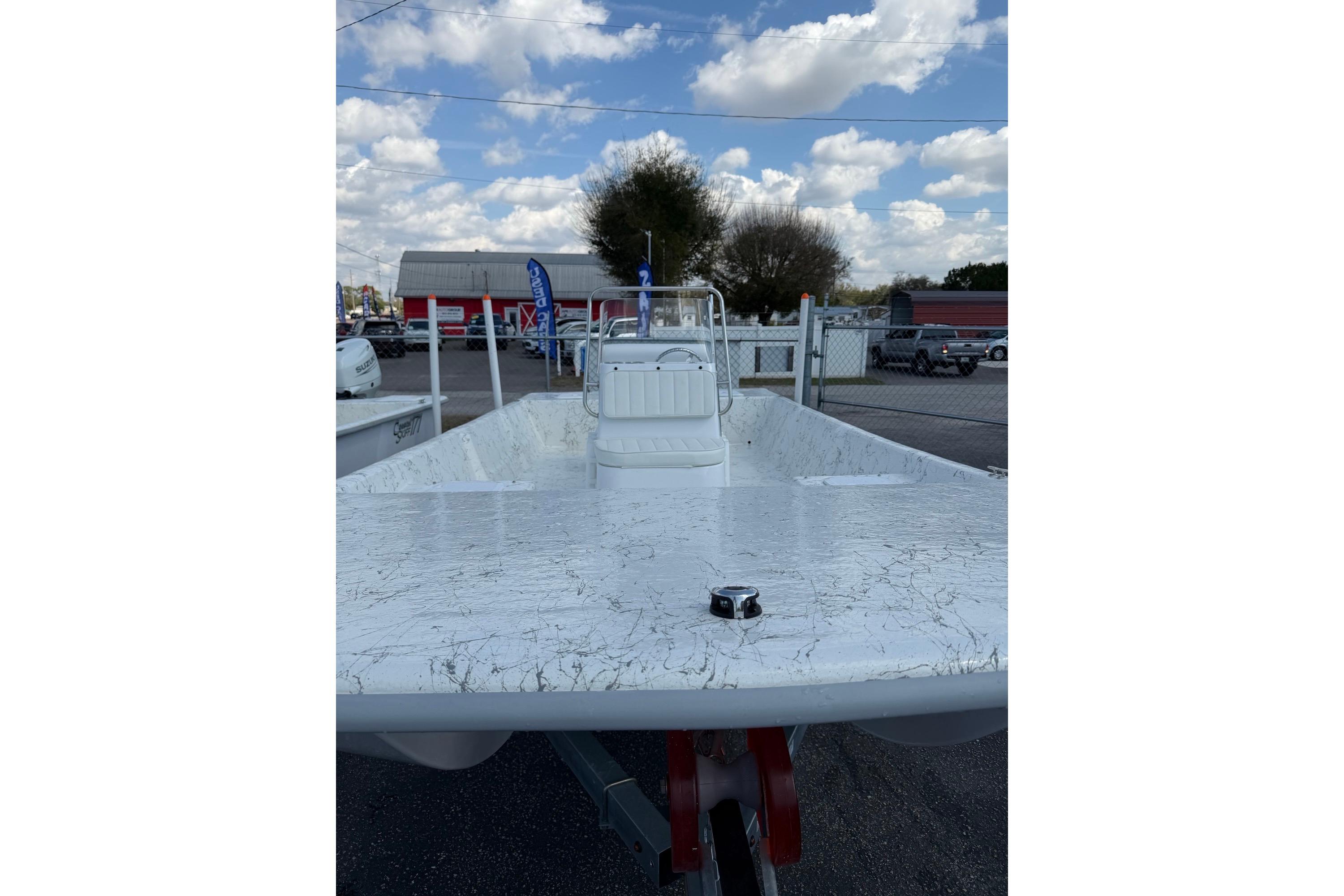 2027 Coastal Skiff 184 boat with white deck, parked outdoors under a cloudy sky.